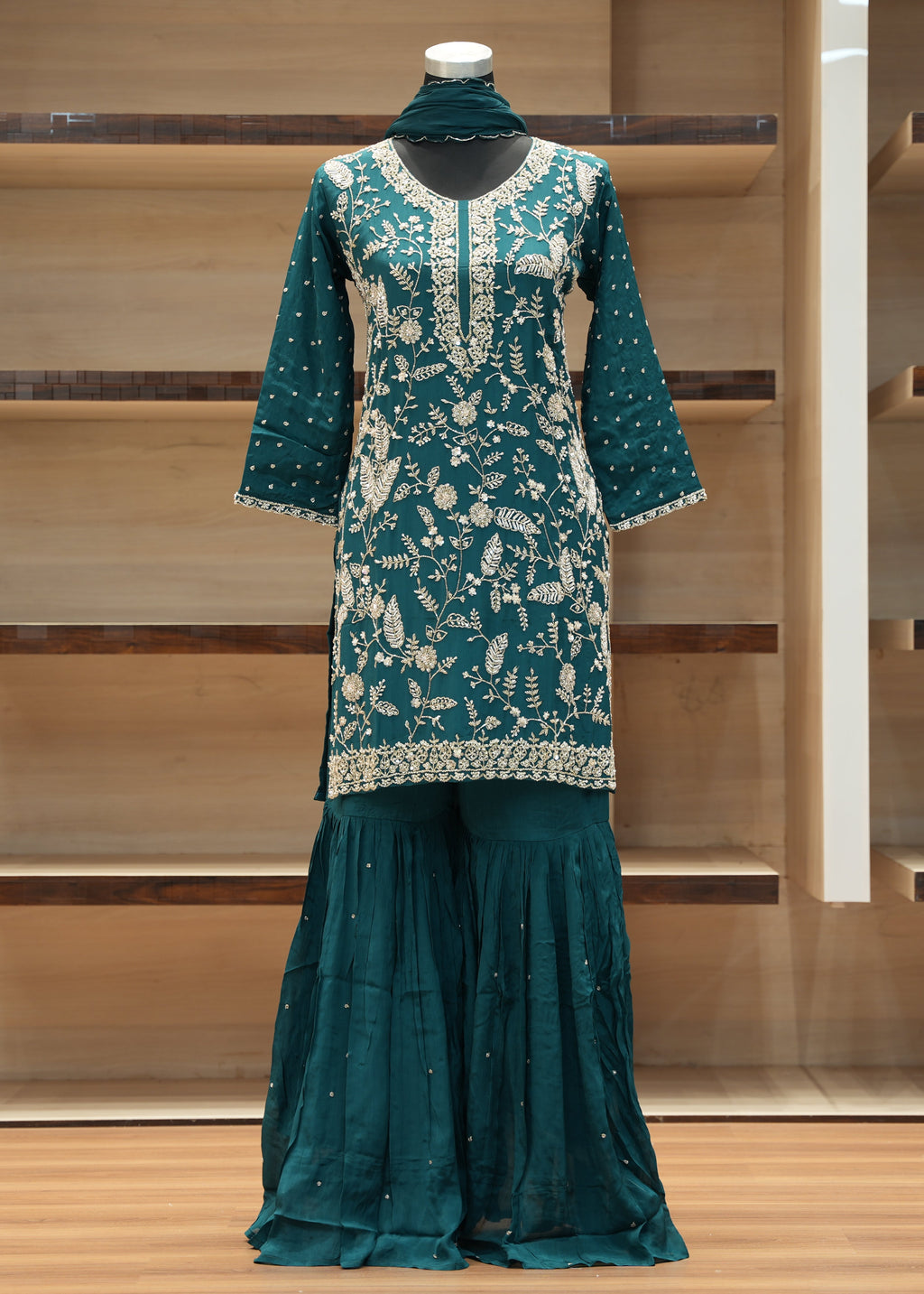 Teal traditional outfit with white patterns on a wooden shelf background