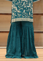 Teal traditional outfit with floral embroidery on a wooden floor