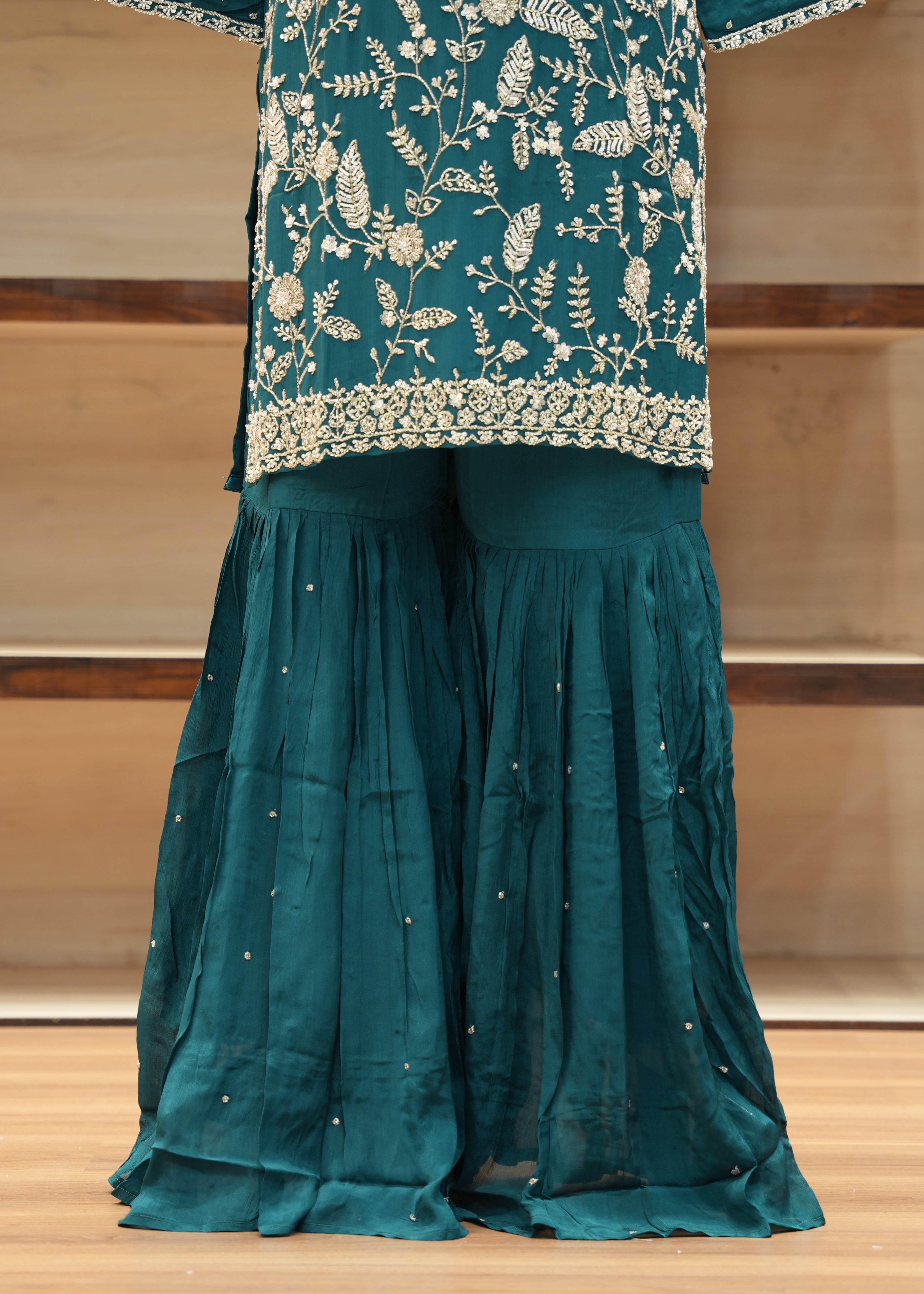 Teal traditional outfit with floral embroidery on a wooden floor
