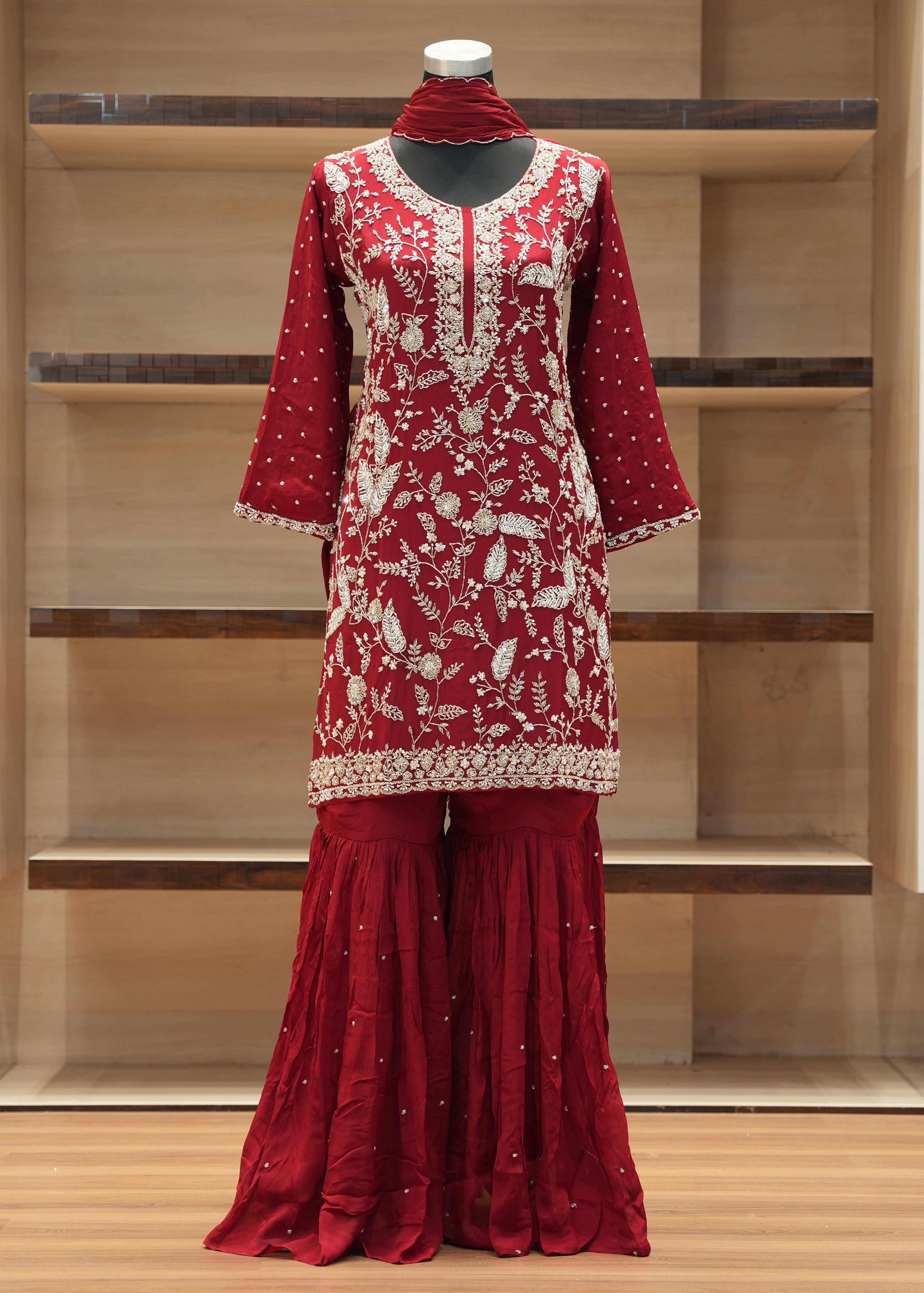 Red embroidered traditional outfit on a mannequin against a wooden background