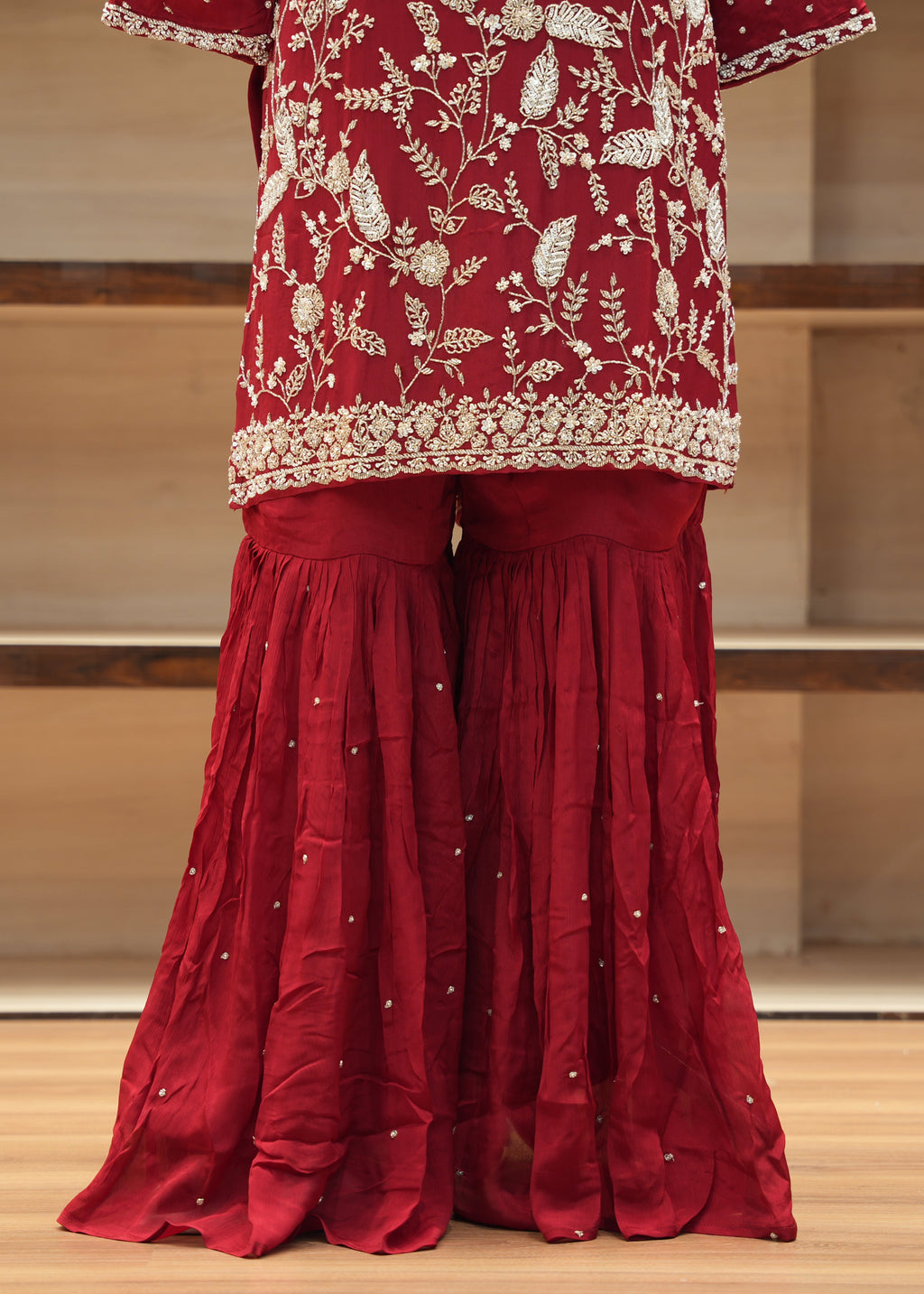 Red traditional outfit with floral patterns on a wooden floor