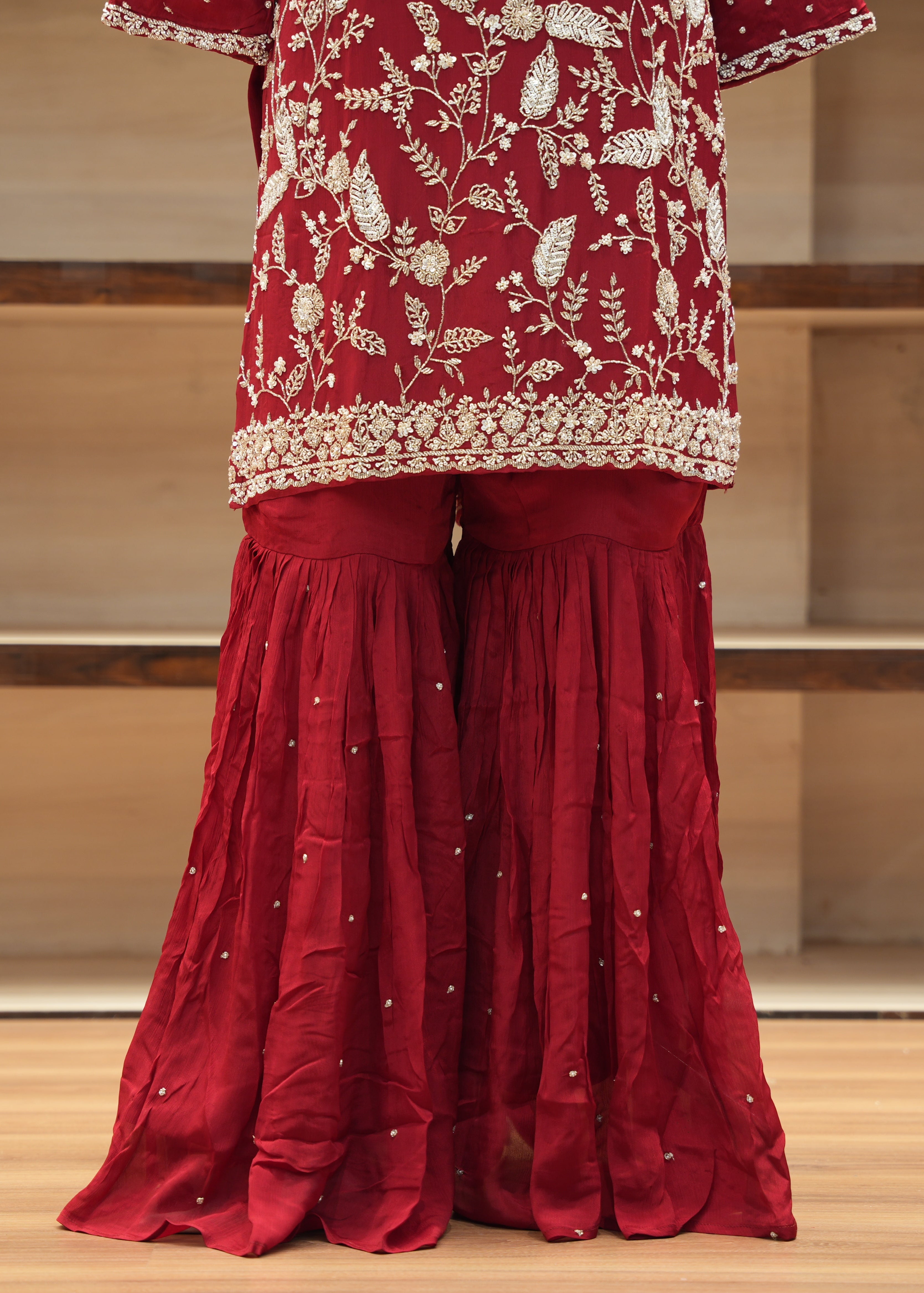 Red traditional outfit with floral patterns on a wooden floor