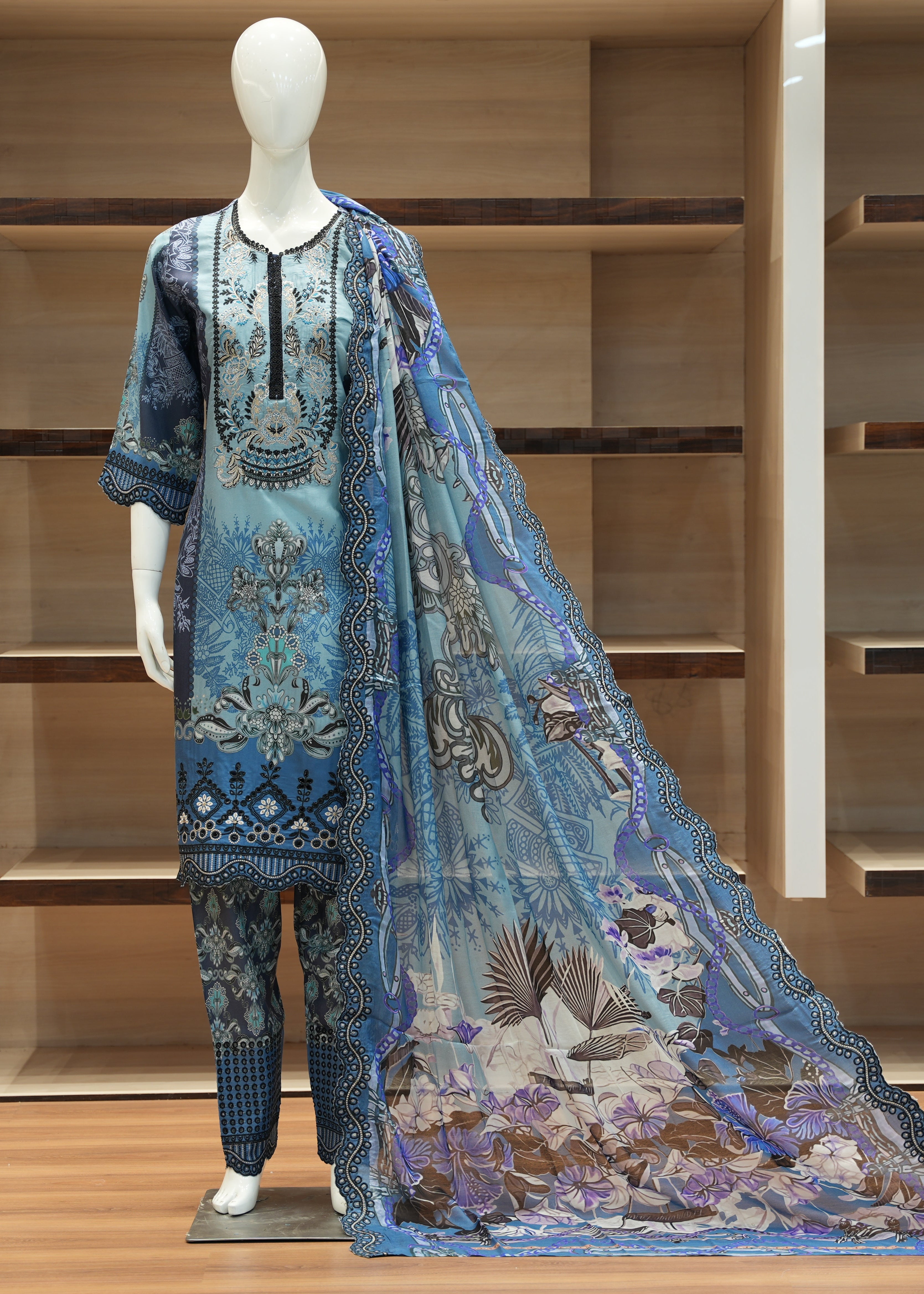 Mannequin wearing a blue embroidered outfit with a matching dupatta against a wooden background