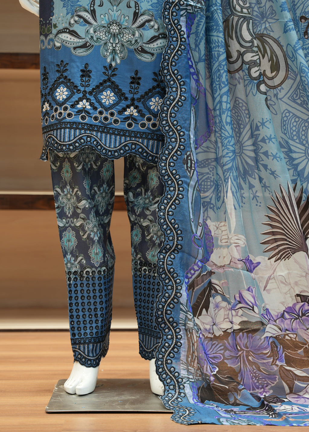 Mannequin wearing a blue and patterned outfit on a wooden floor.