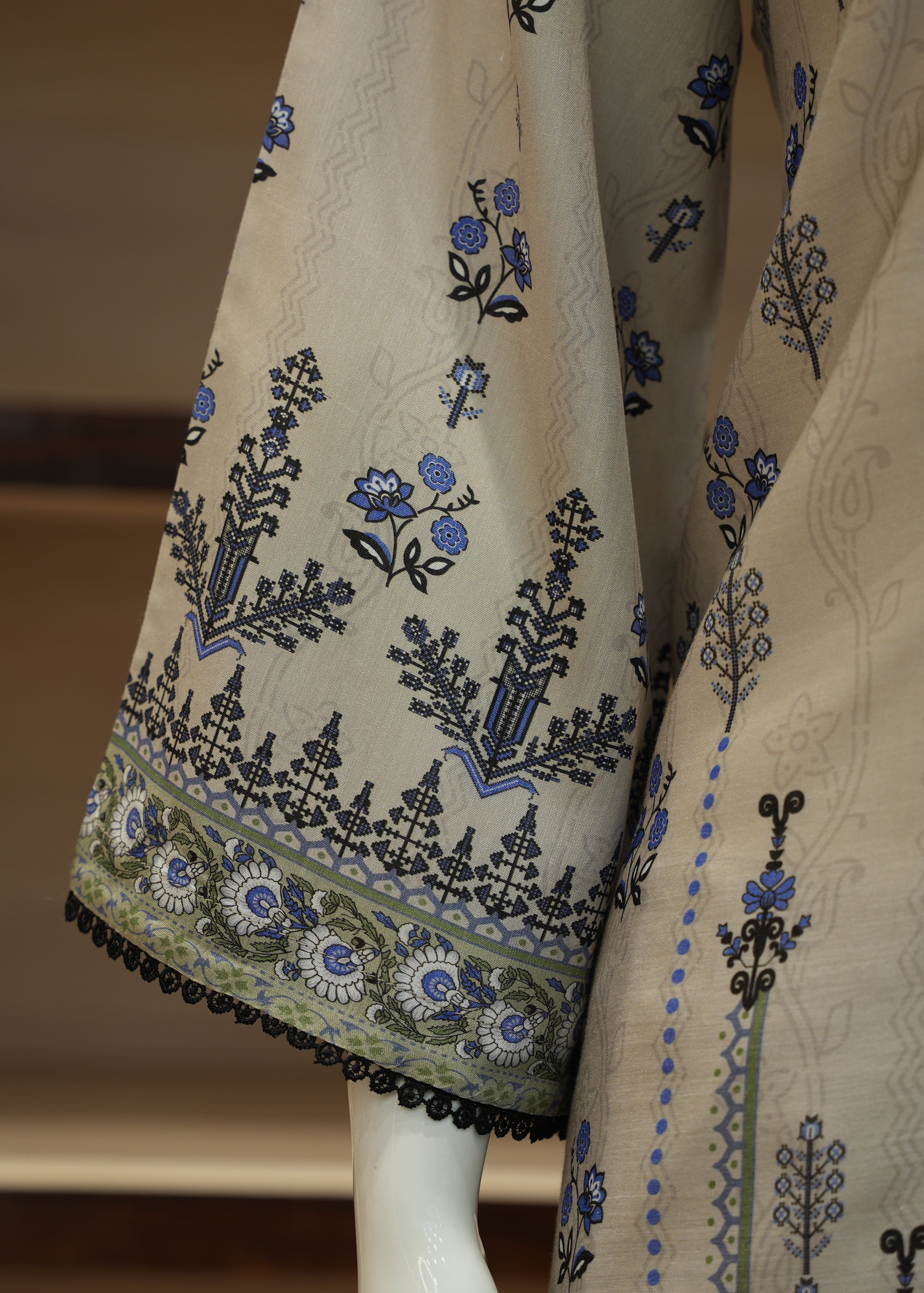 Beige fabric with black and blue floral embroidery on a mannequin.