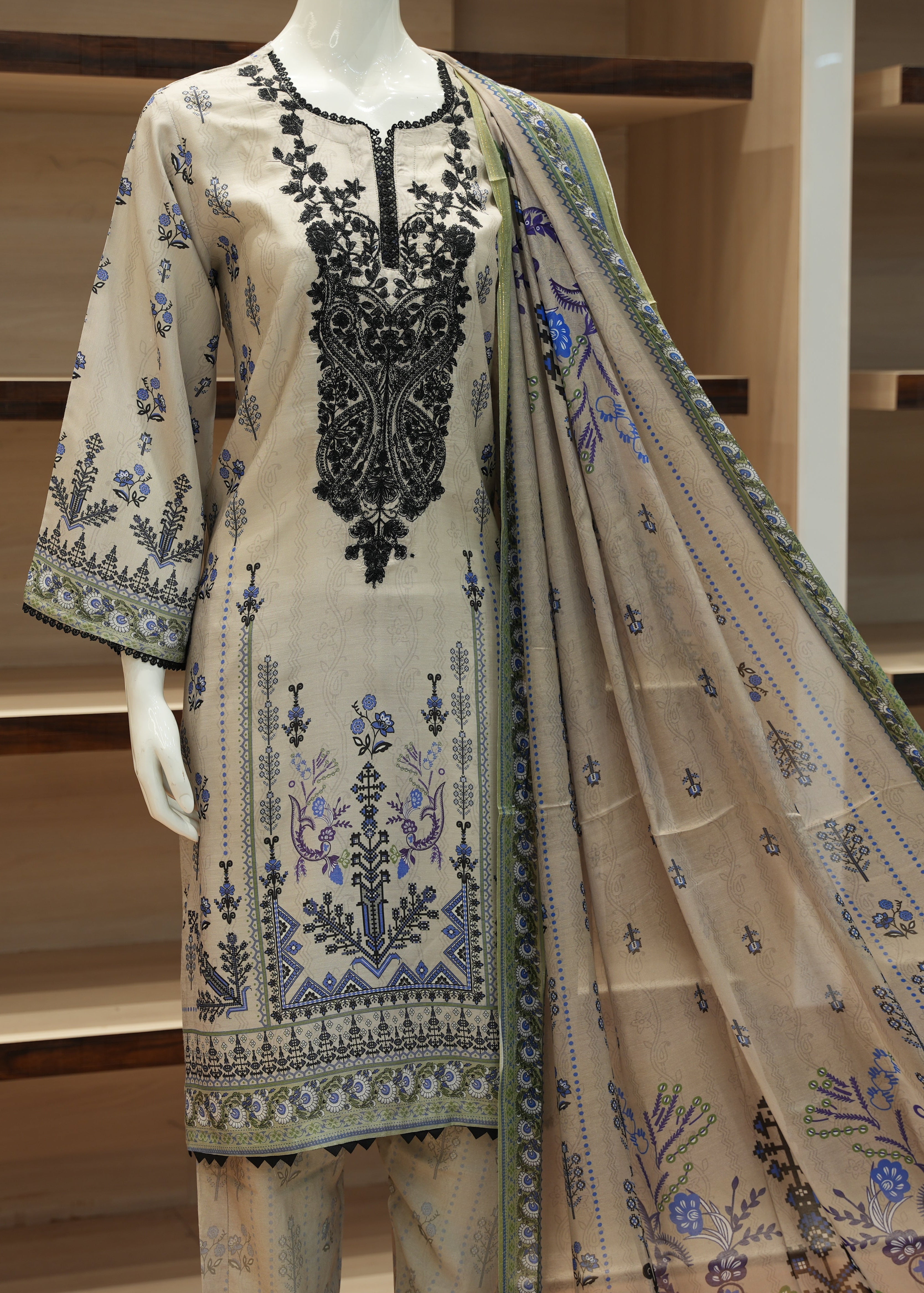 Embroidered outfit with a dupatta on a mannequin against a wooden background