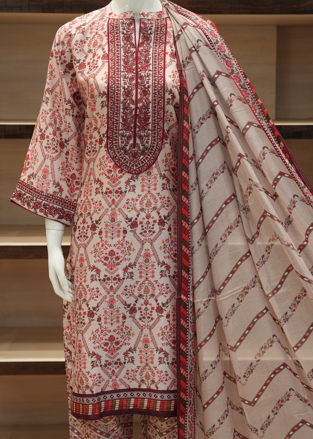 Traditional embroidered outfit with a dupatta on a mannequin against a neutral background