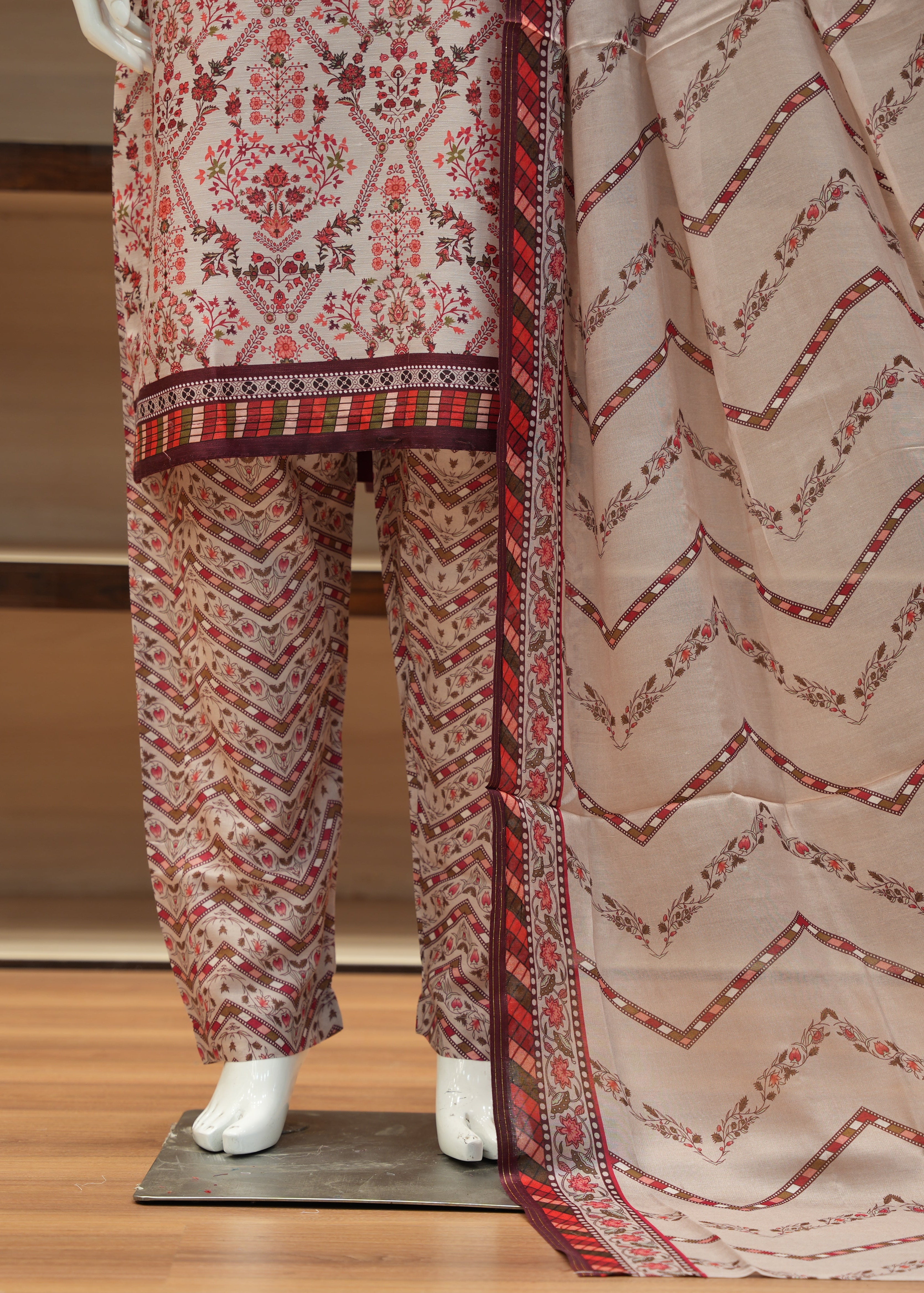 Mannequin wearing a patterned outfit with a sheer dupatta in a store setting.
