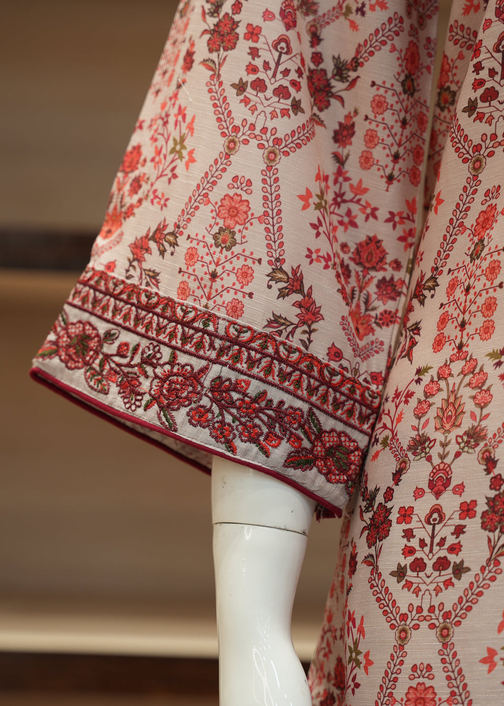 Mannequin wearing a floral patterned garment with red and brown details.