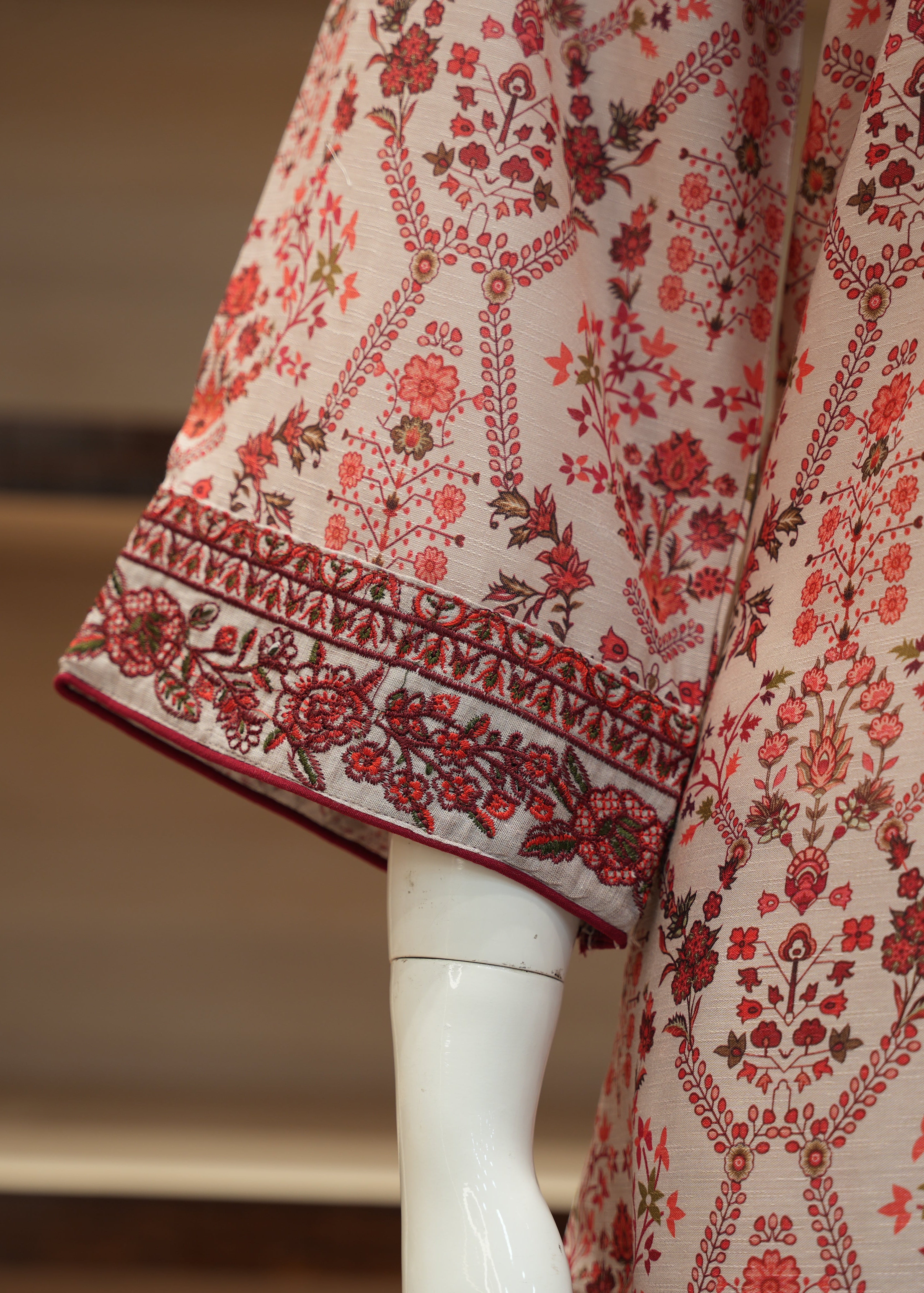 Mannequin wearing a floral patterned garment with red and brown details.