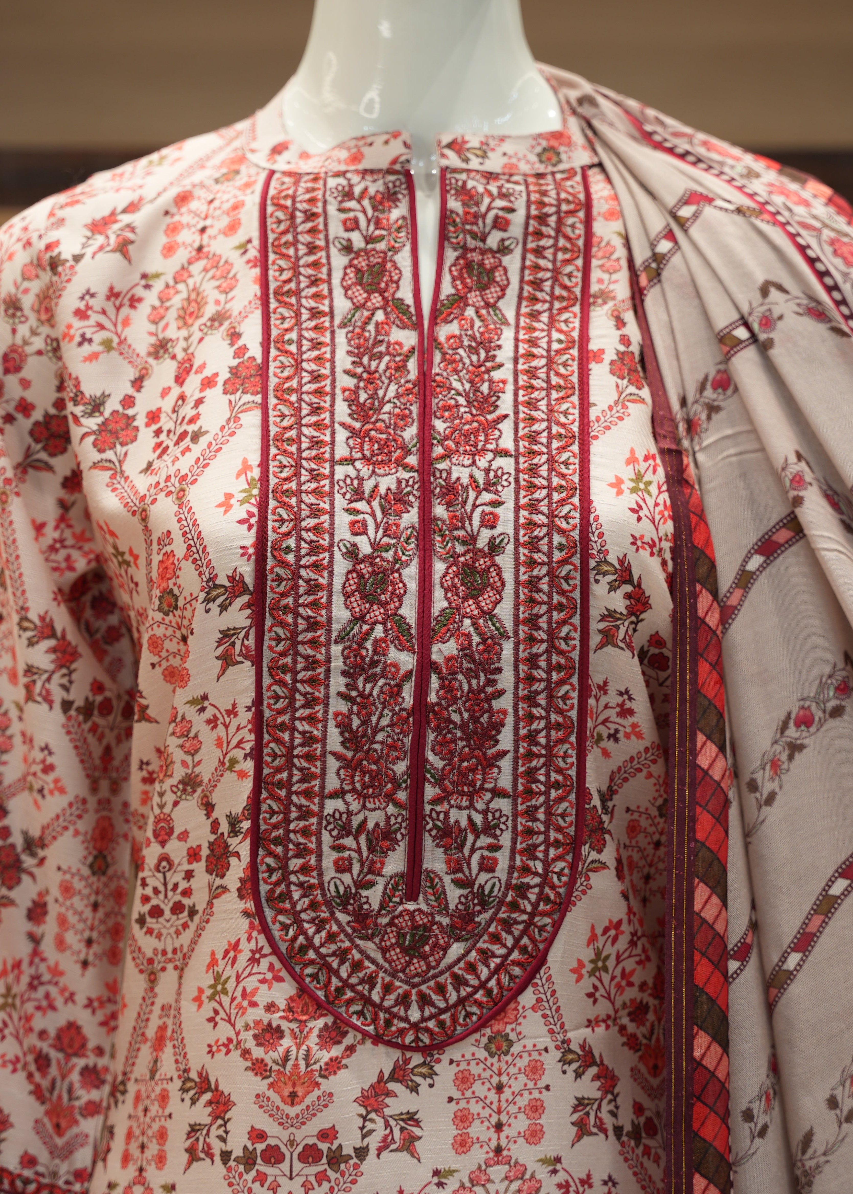 Embroidered garment with red and black patterns on a neutral background