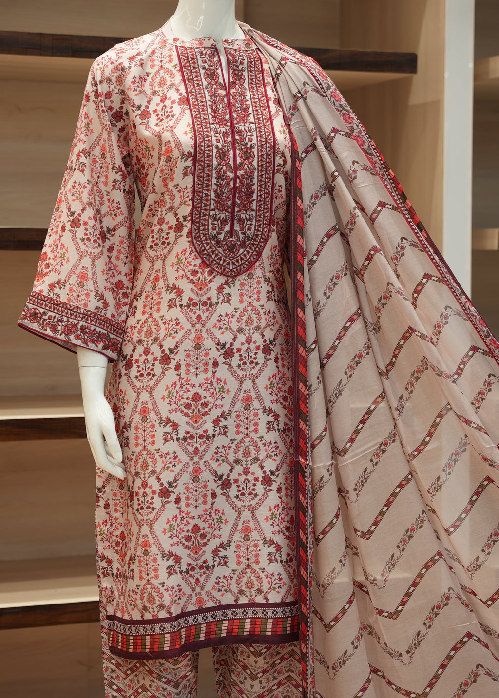 Mannequin wearing a patterned outfit with a matching shawl against a neutral background