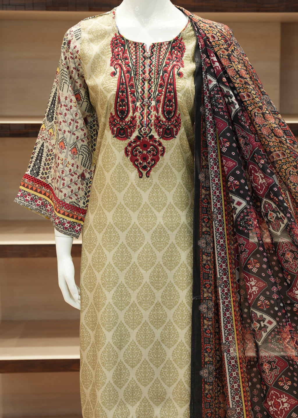 Traditional embroidered outfit with a patterned shawl on a mannequin against a neutral background