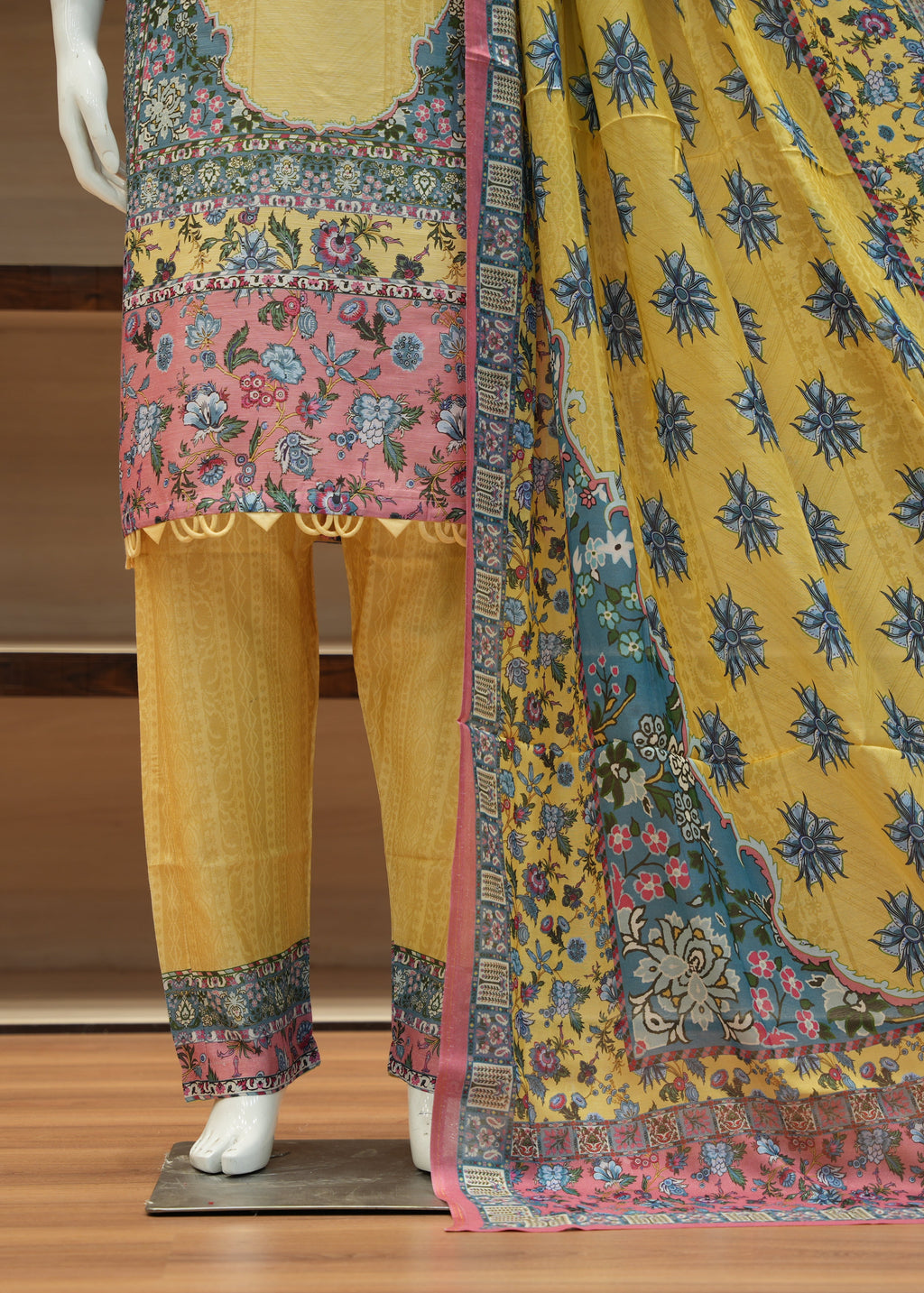 Traditional outfit with a yellow kurta, pants, and dupatta on a wooden stand.