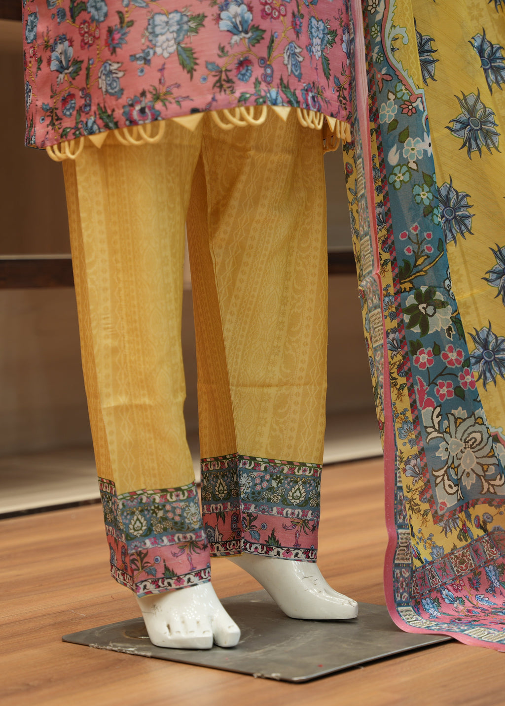 Traditional outfit with yellow pants and floral dupatta on a wooden floor.