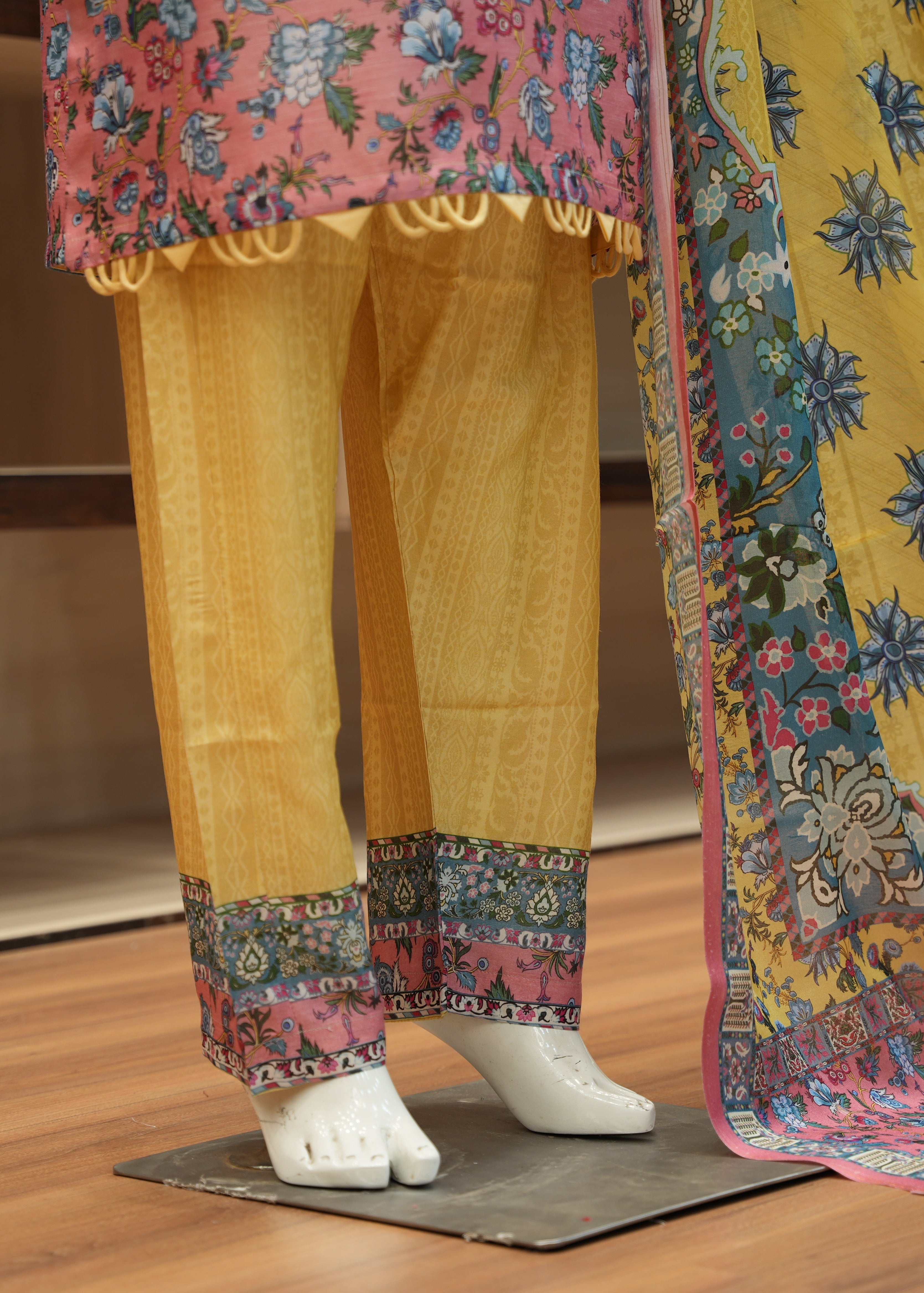 Traditional outfit with yellow pants and floral dupatta on a wooden floor.