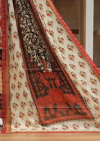 Traditional patterned fabric with red, black, and beige colors on a wooden floor.