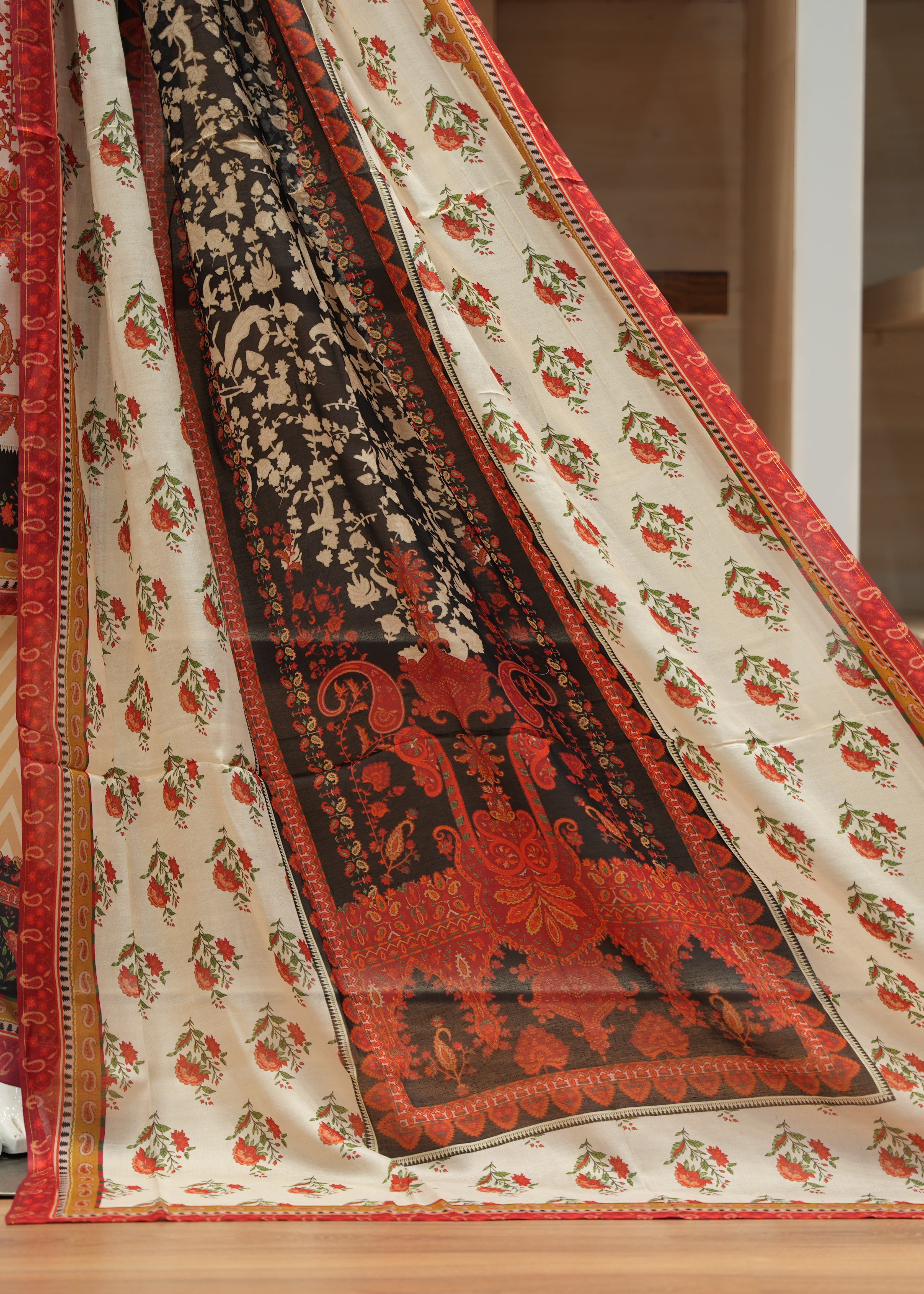 Traditional patterned fabric with red, black, and beige colors on a wooden floor.