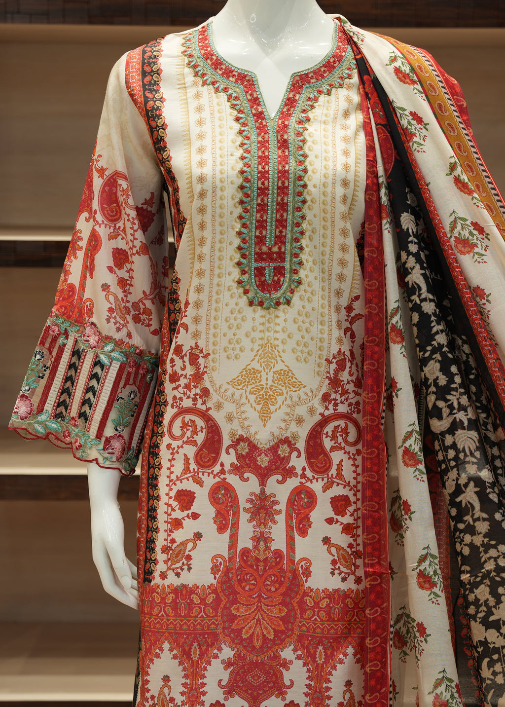 Traditional embroidered outfit with a shawl on a mannequin against a neutral background