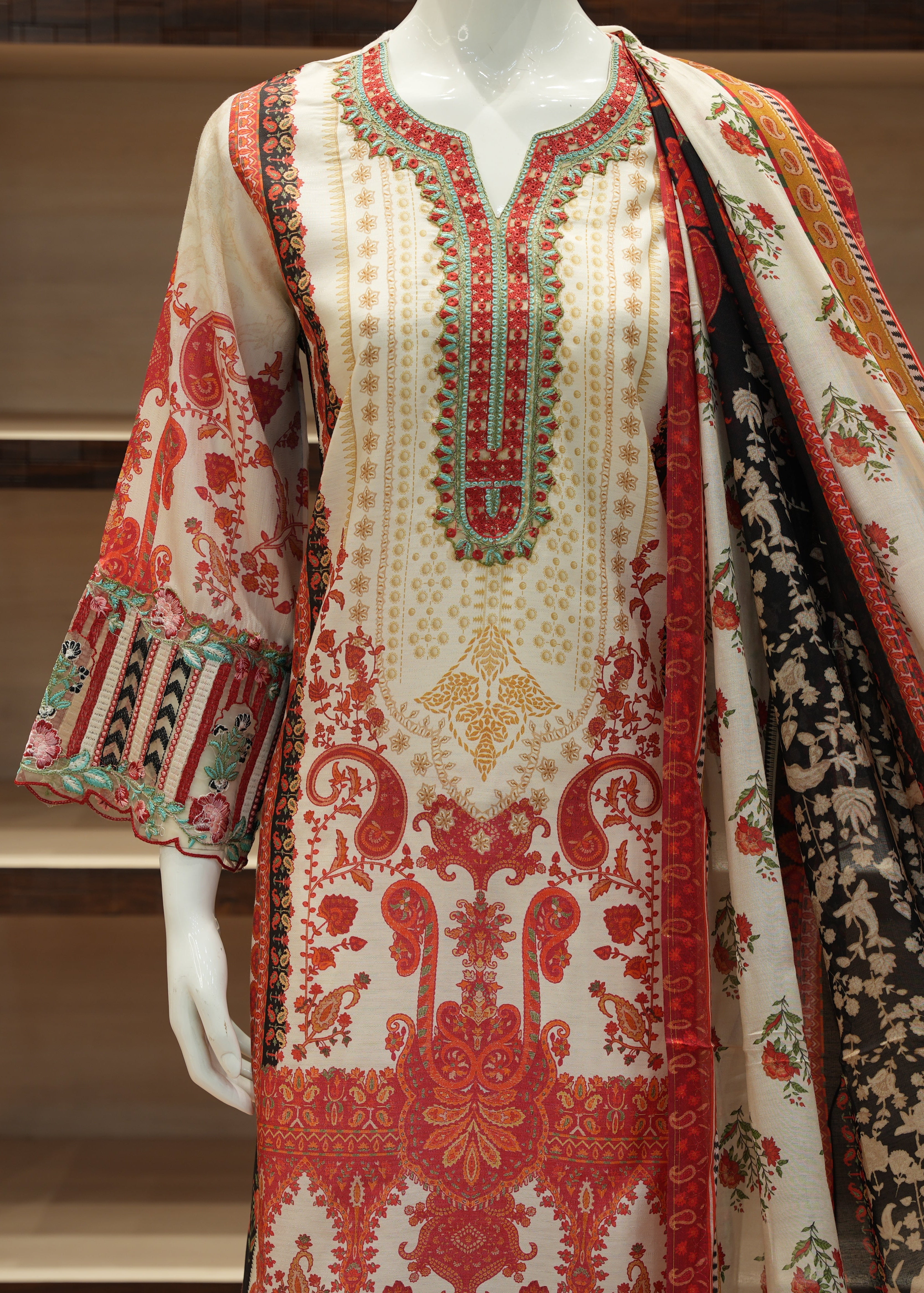 Traditional embroidered outfit with a shawl on a mannequin against a neutral background