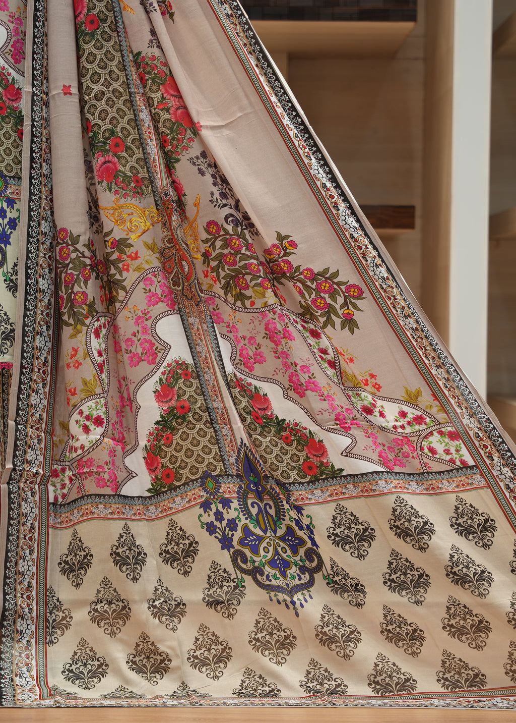 Colorful traditional outfit with floral and paisley patterns on a wooden floor.