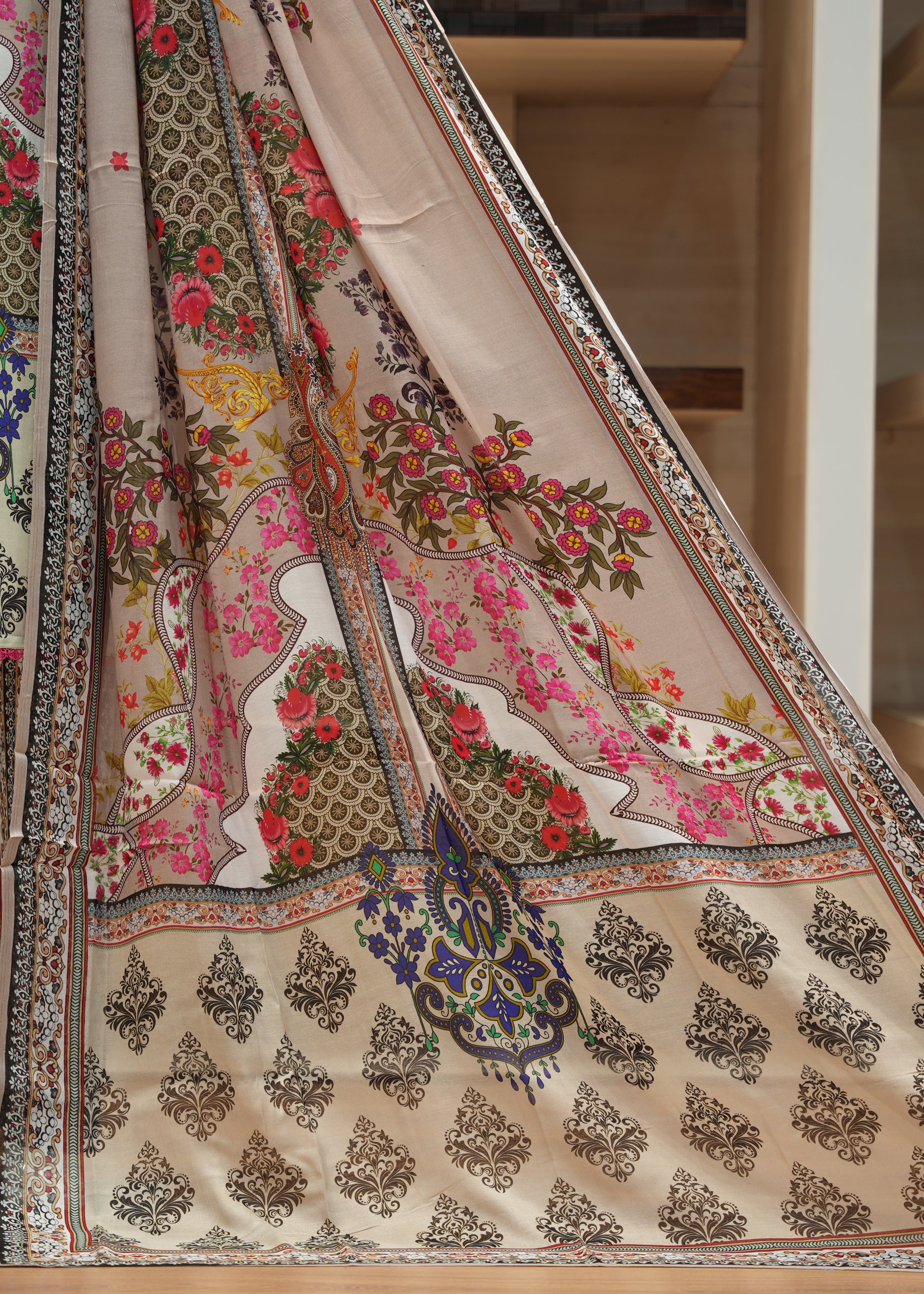 Colorful traditional outfit with floral and paisley patterns on a wooden floor.