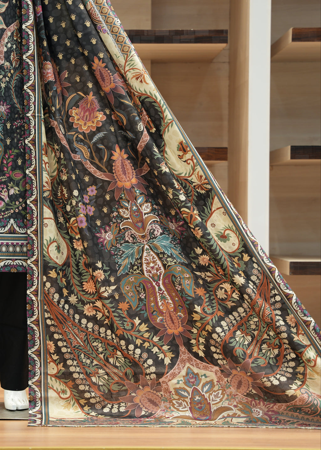 Mannequin wearing a patterned outfit with a large fabric swatch displaying intricate designs.