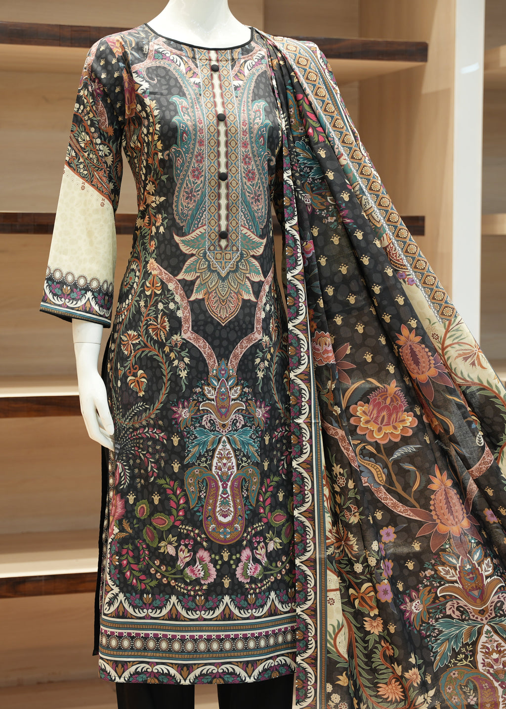 Mannequin wearing a patterned dress with a long scarf in a store setting