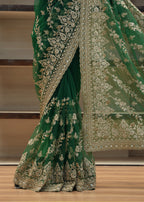 Green embroidered fabric draped over a chair with a blurred background