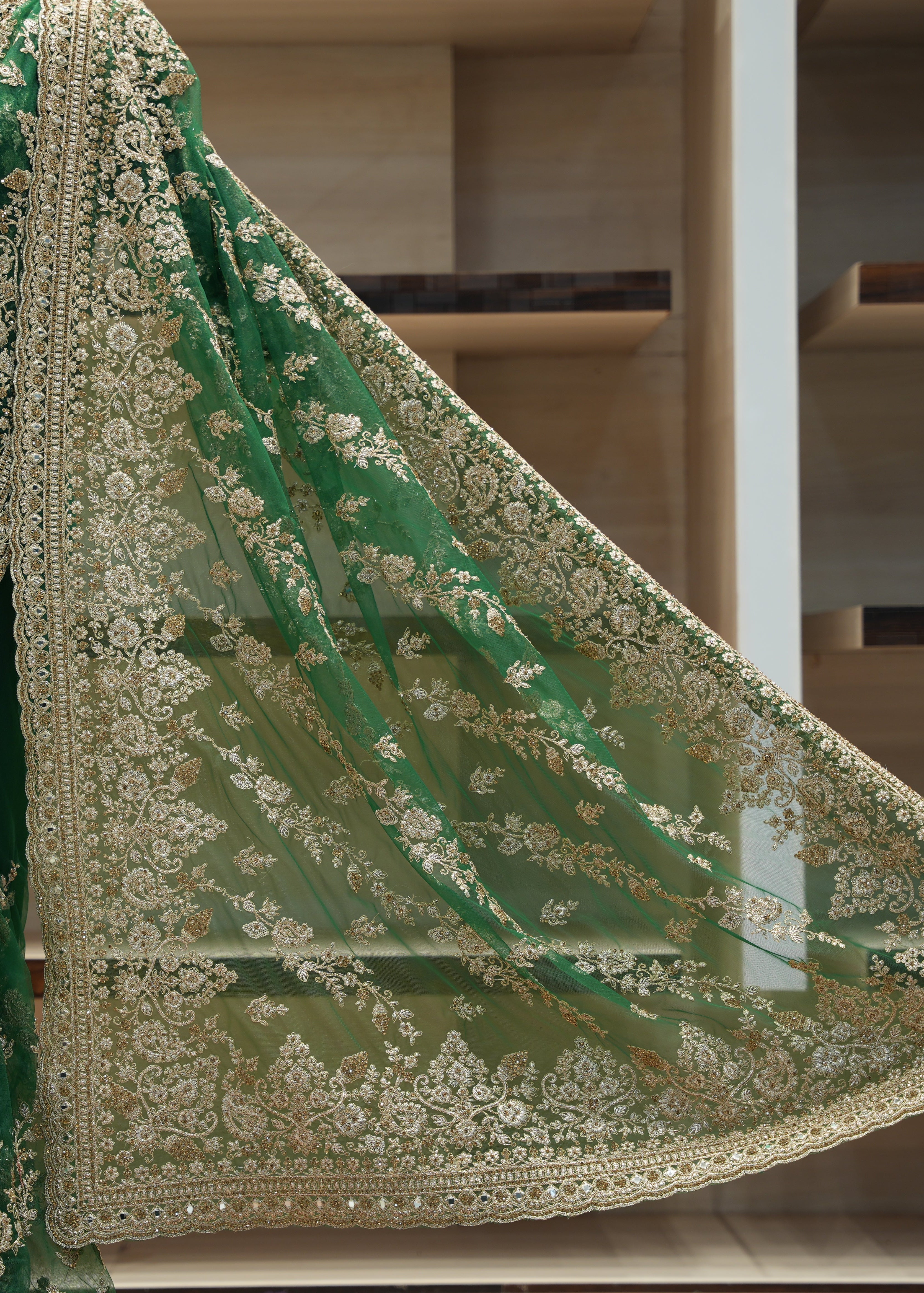 Green embroidered saree with gold detailing on a mannequin against a neutral background
