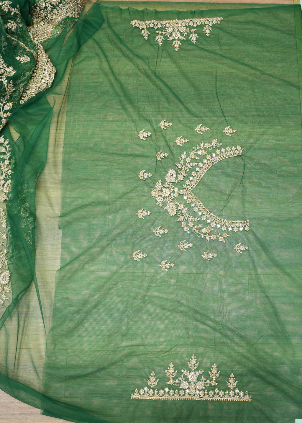 Green fabric with intricate white embroidery on a white floor