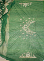 Green fabric with intricate white embroidery on a white floor