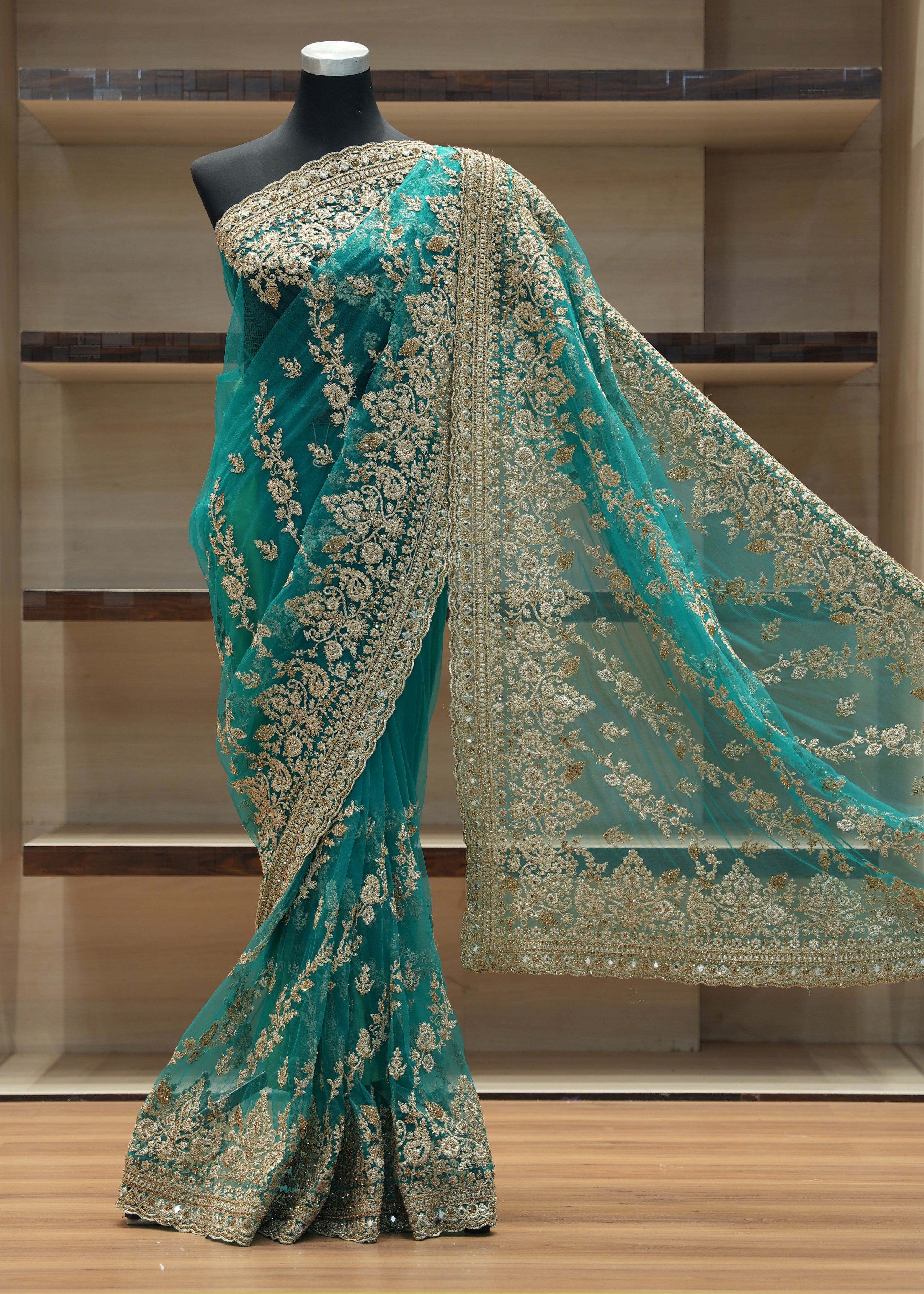 Teal embroidered fabric draped over a black stand against a wooden background