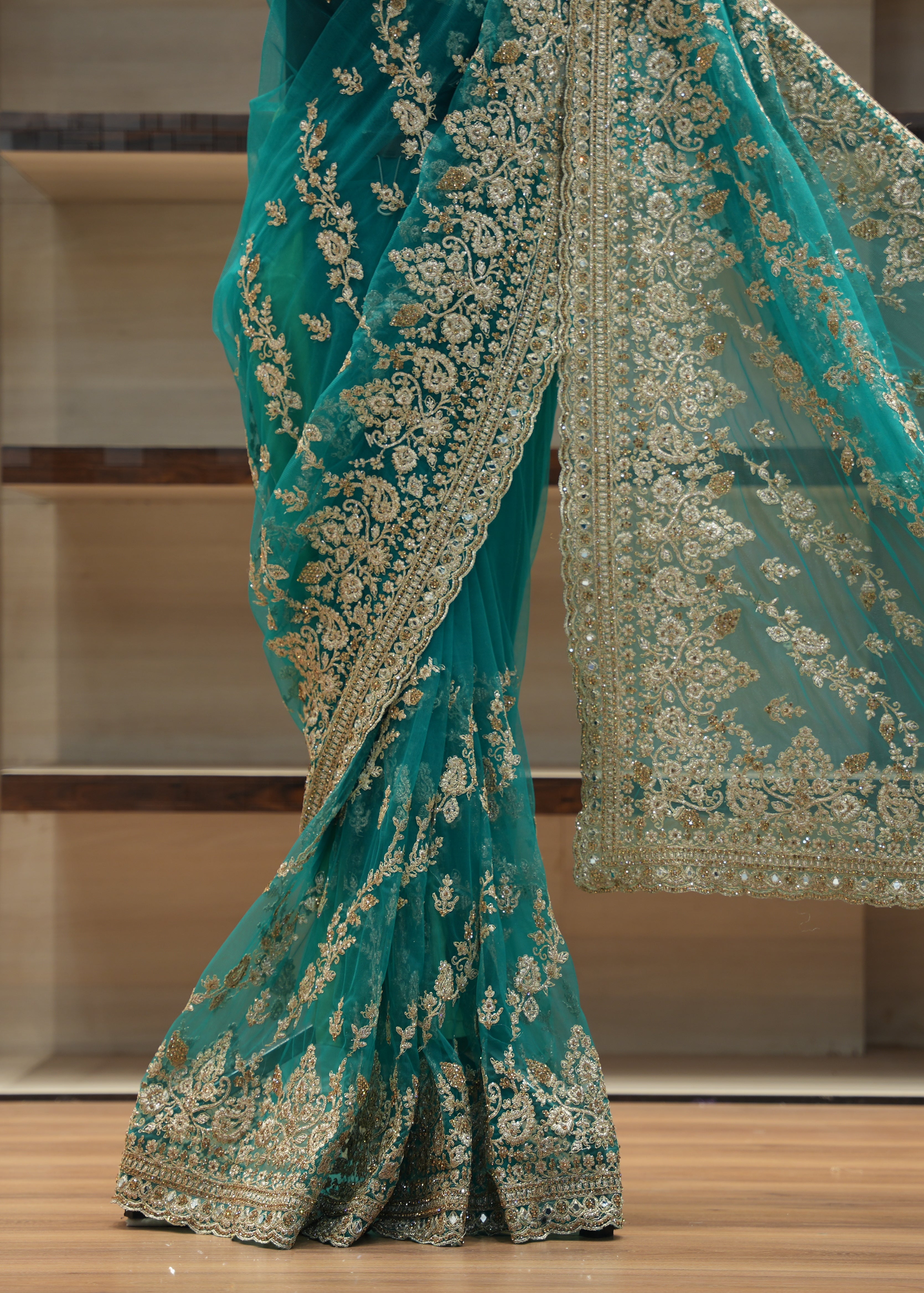 Teal saree with gold embroidery on a wooden floor