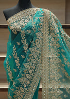 Teal saree with gold embroidery on a mannequin against a neutral background