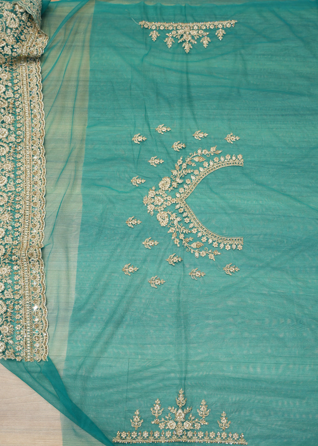 Teal fabric with gold embroidery on a white background