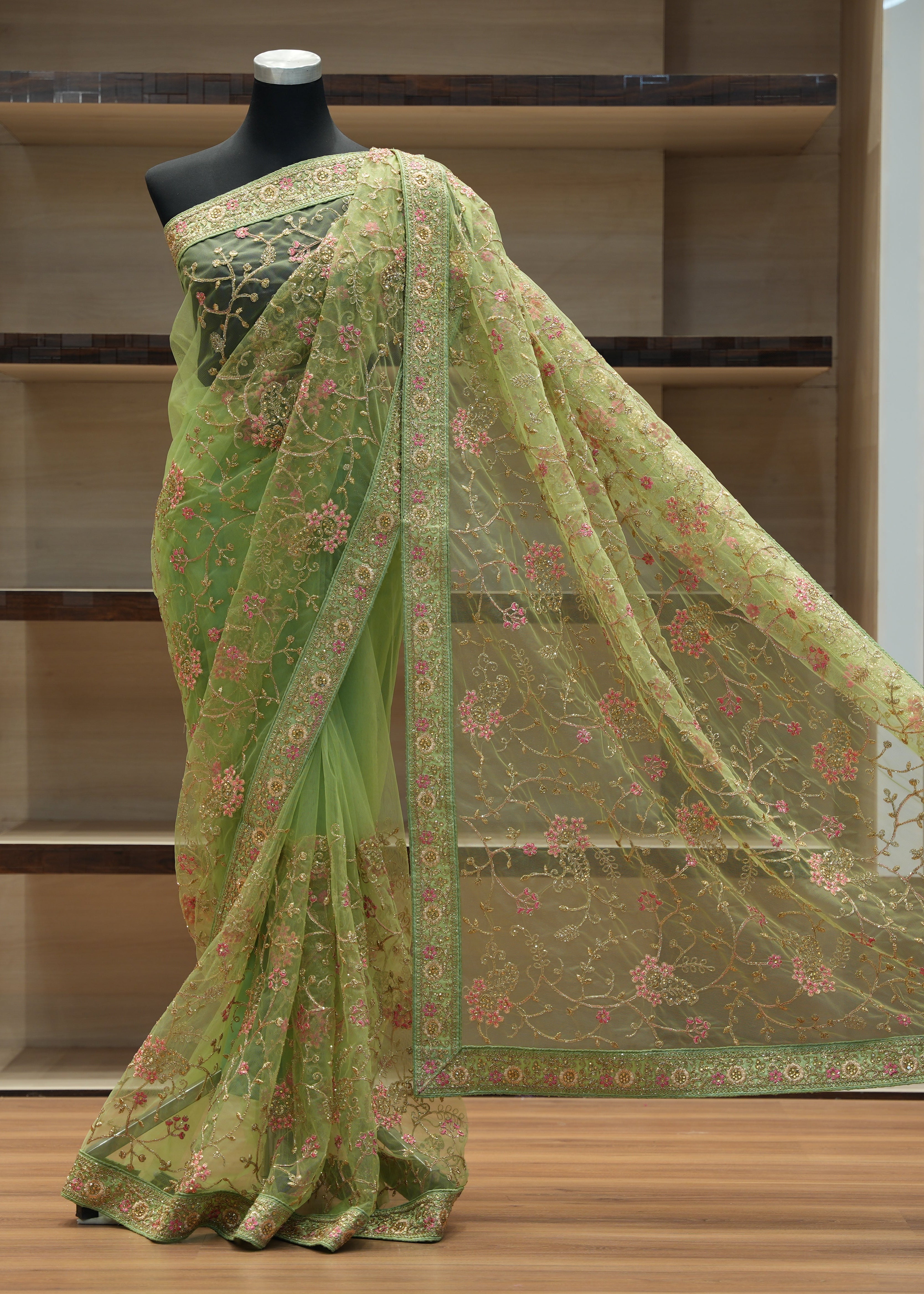Green saree with floral patterns on a mannequin against a neutral background