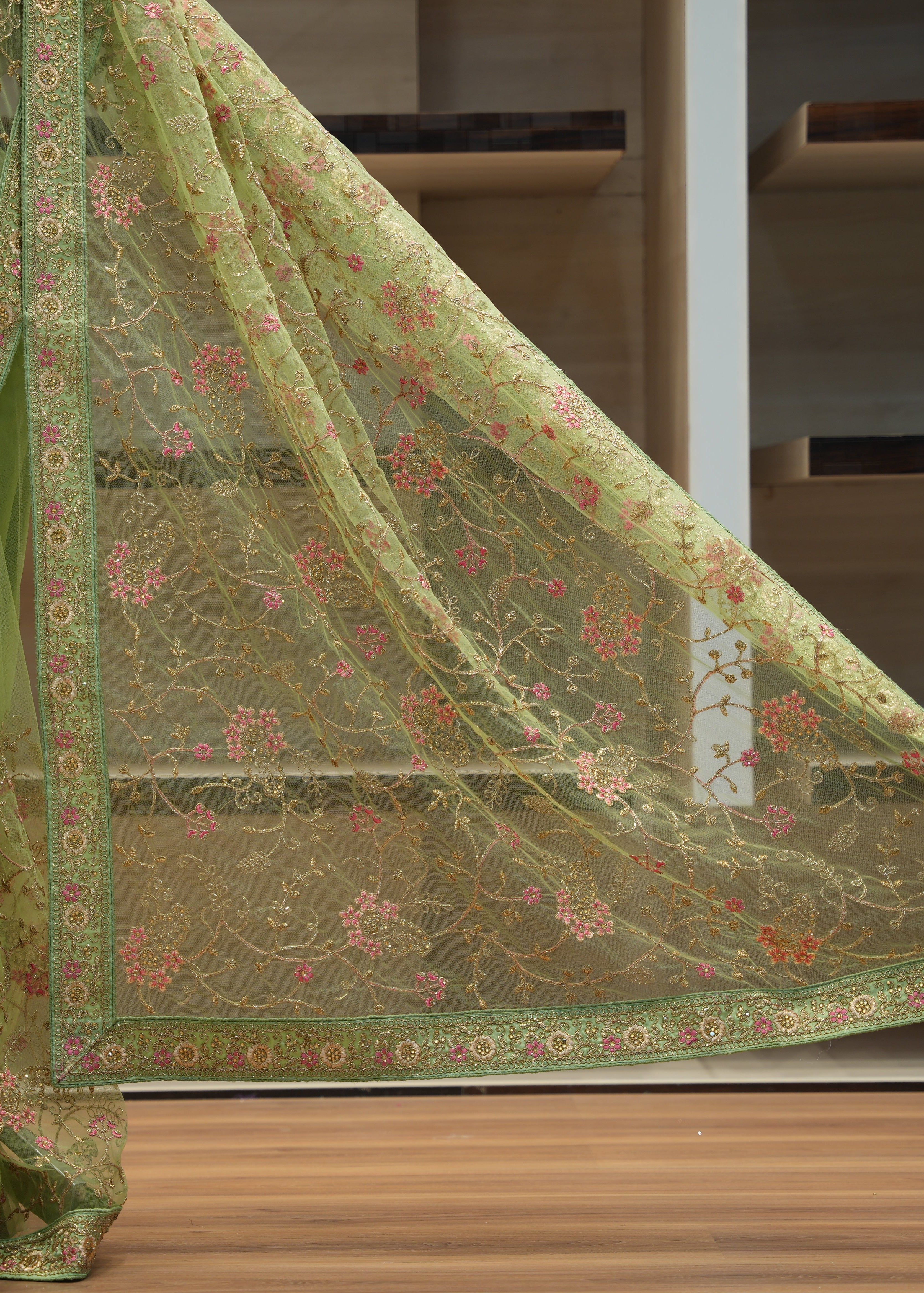 Green embroidered saree with a blurred indoor background