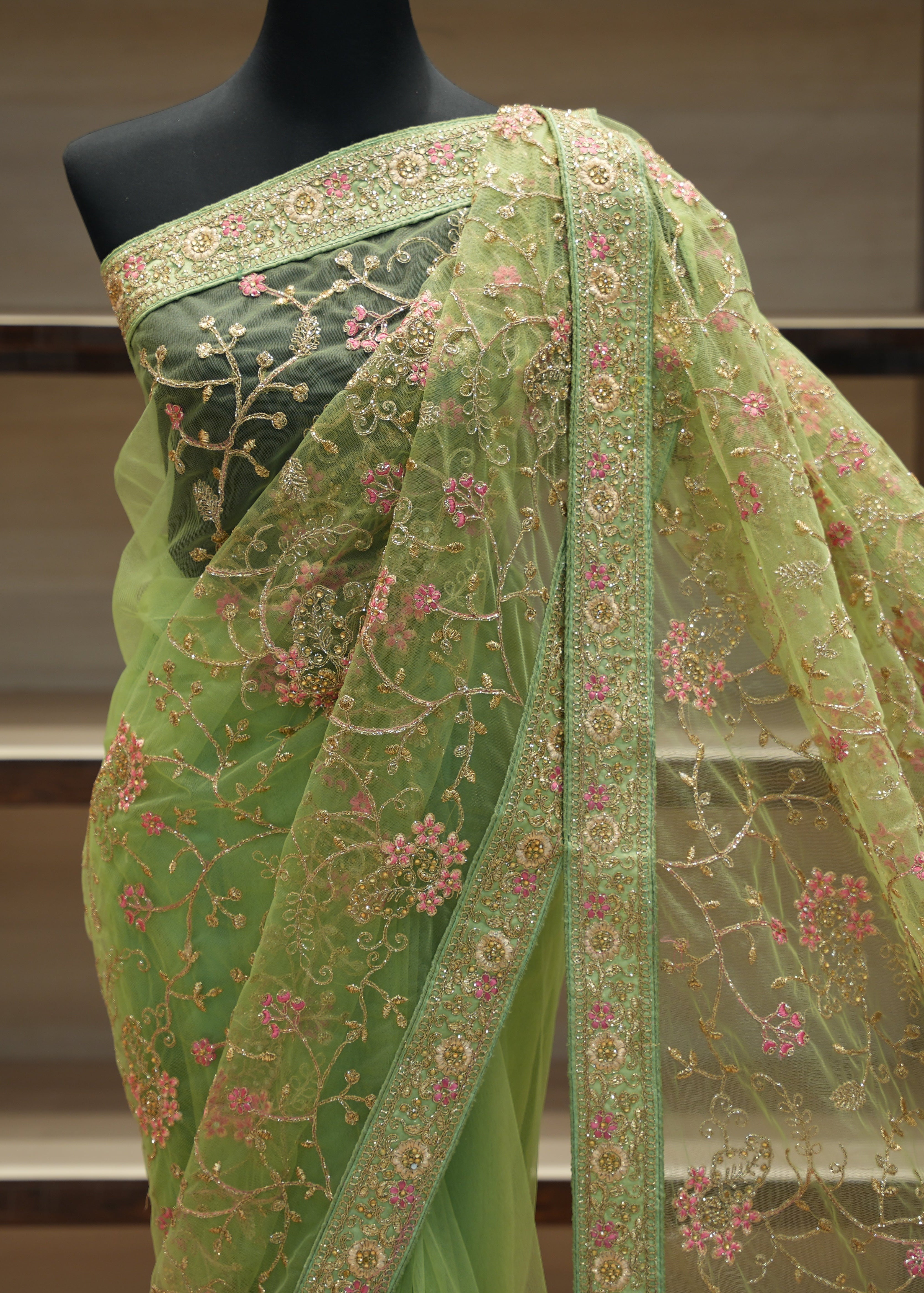Green embroidered saree on a mannequin against a neutral background