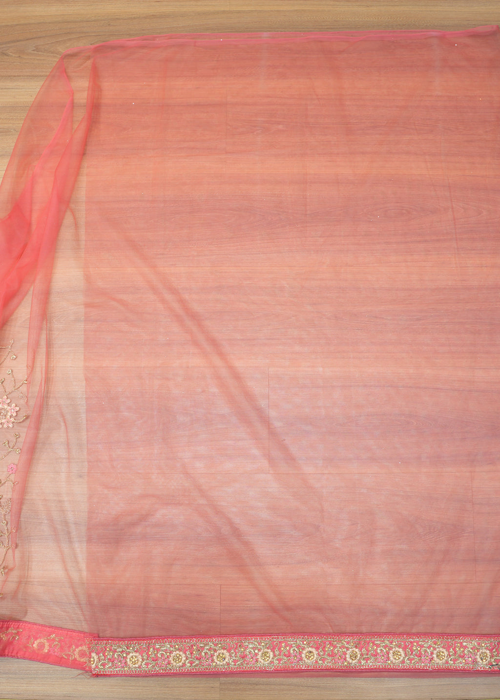 Saree with a red and gold border on a wooden surface