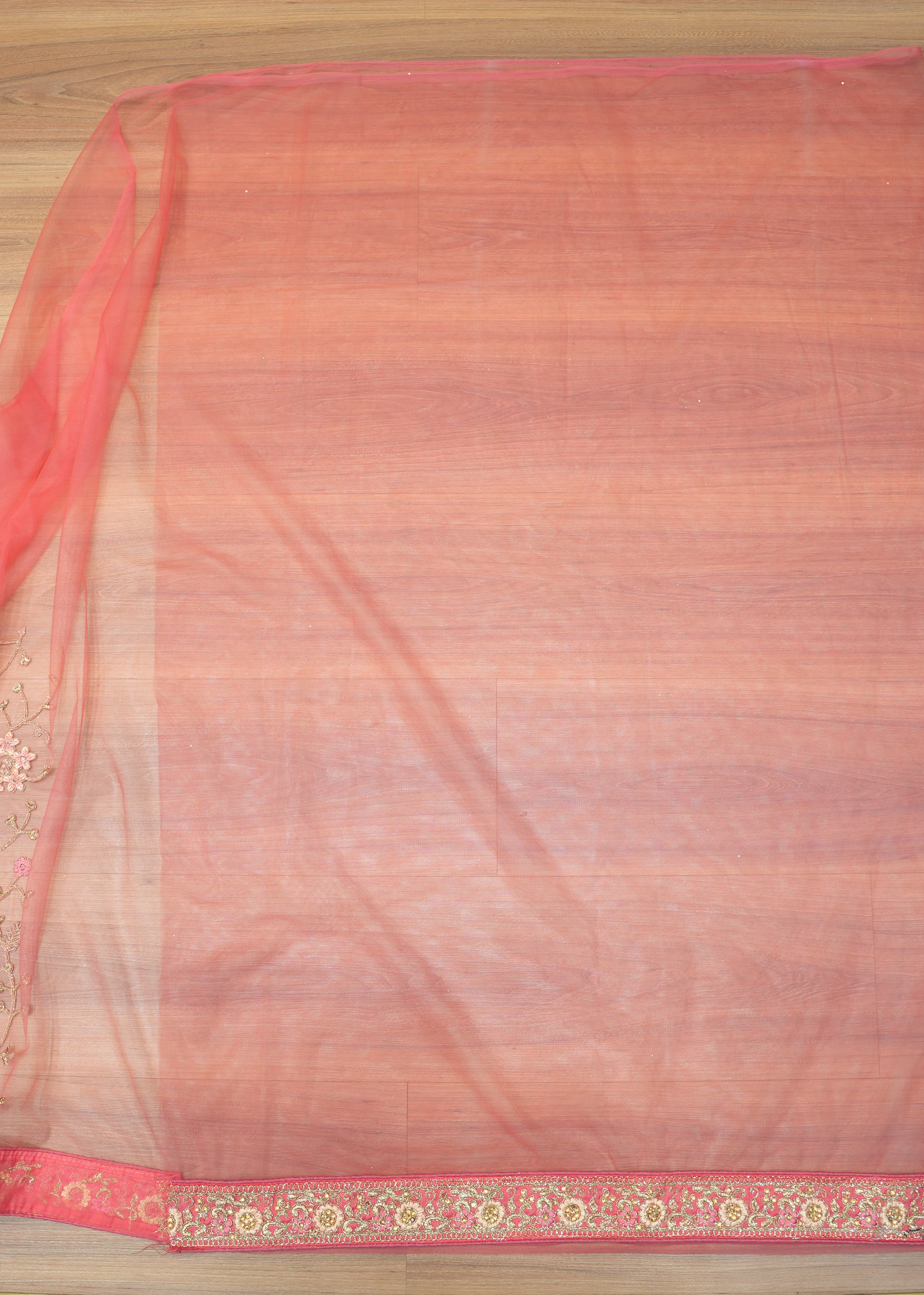 Saree with a red and gold border on a wooden surface