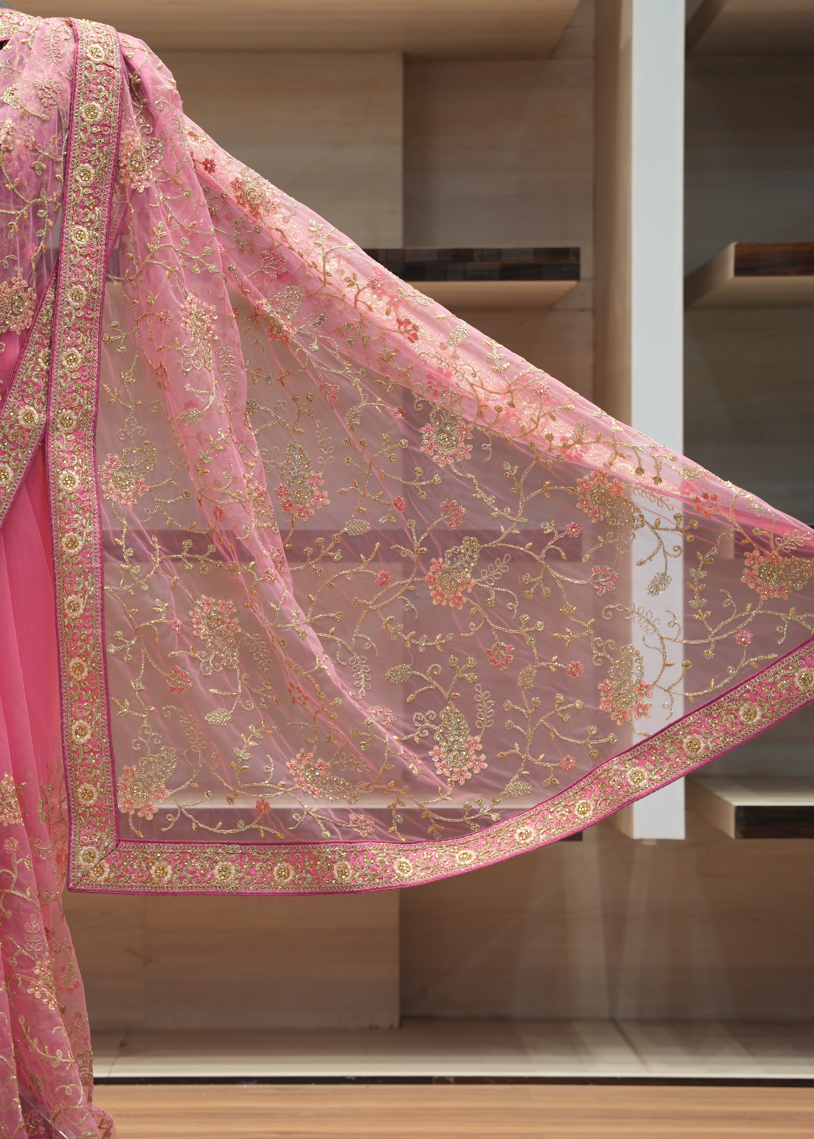 Pink saree with gold embroidery on a wooden surface