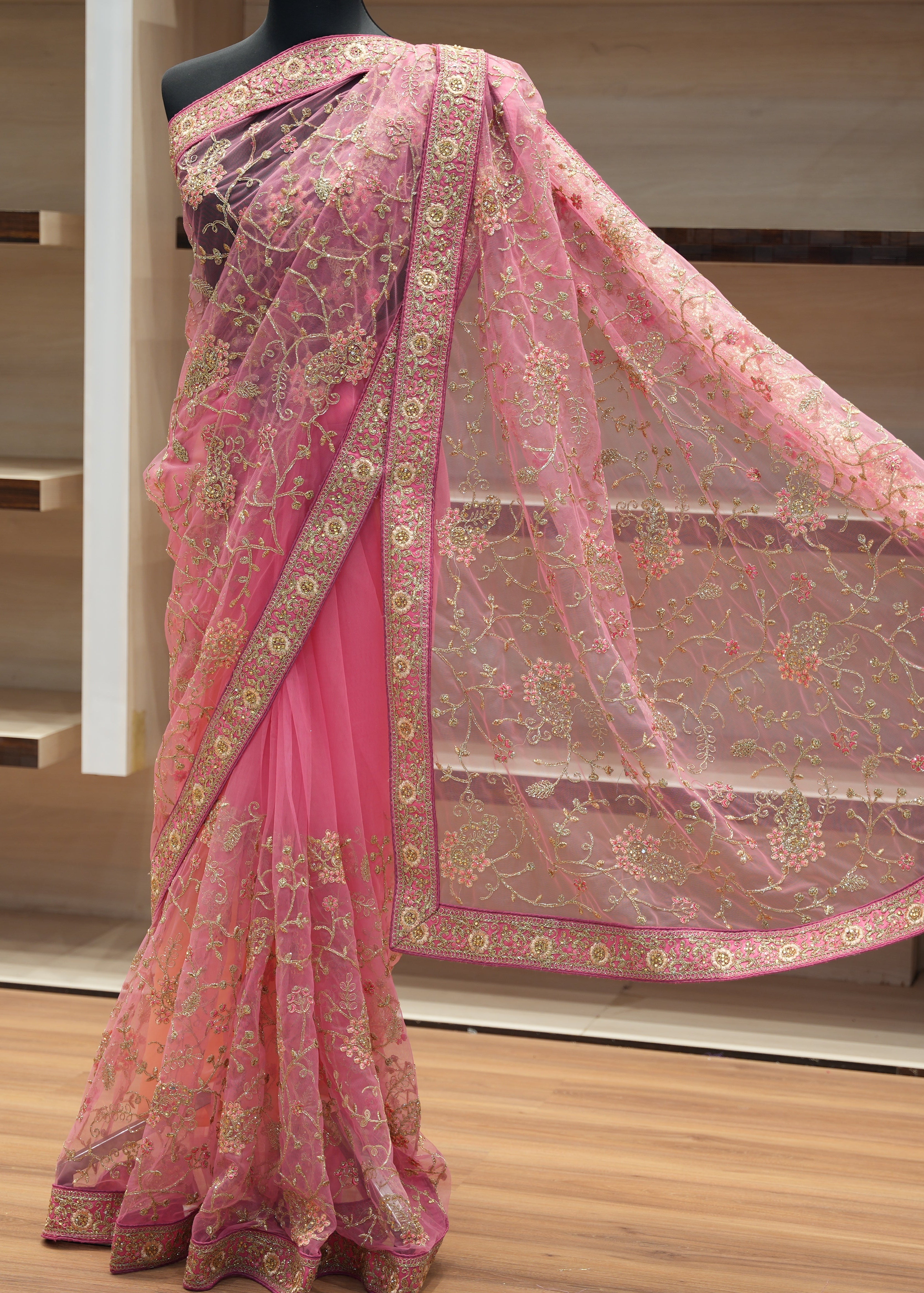 Pink saree with gold embroidery on a mannequin against a neutral background