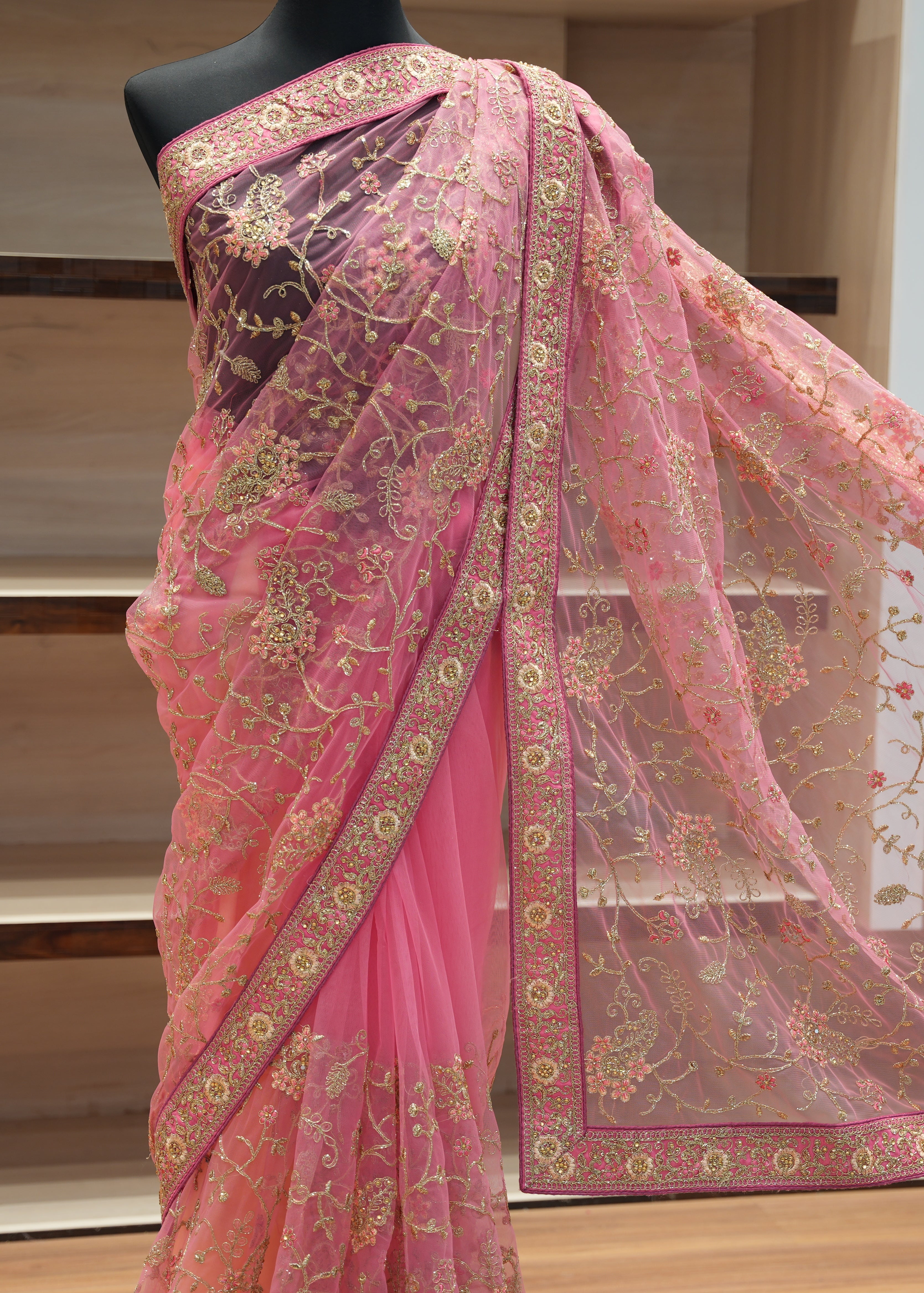Pink saree with floral patterns on a mannequin against a neutral background