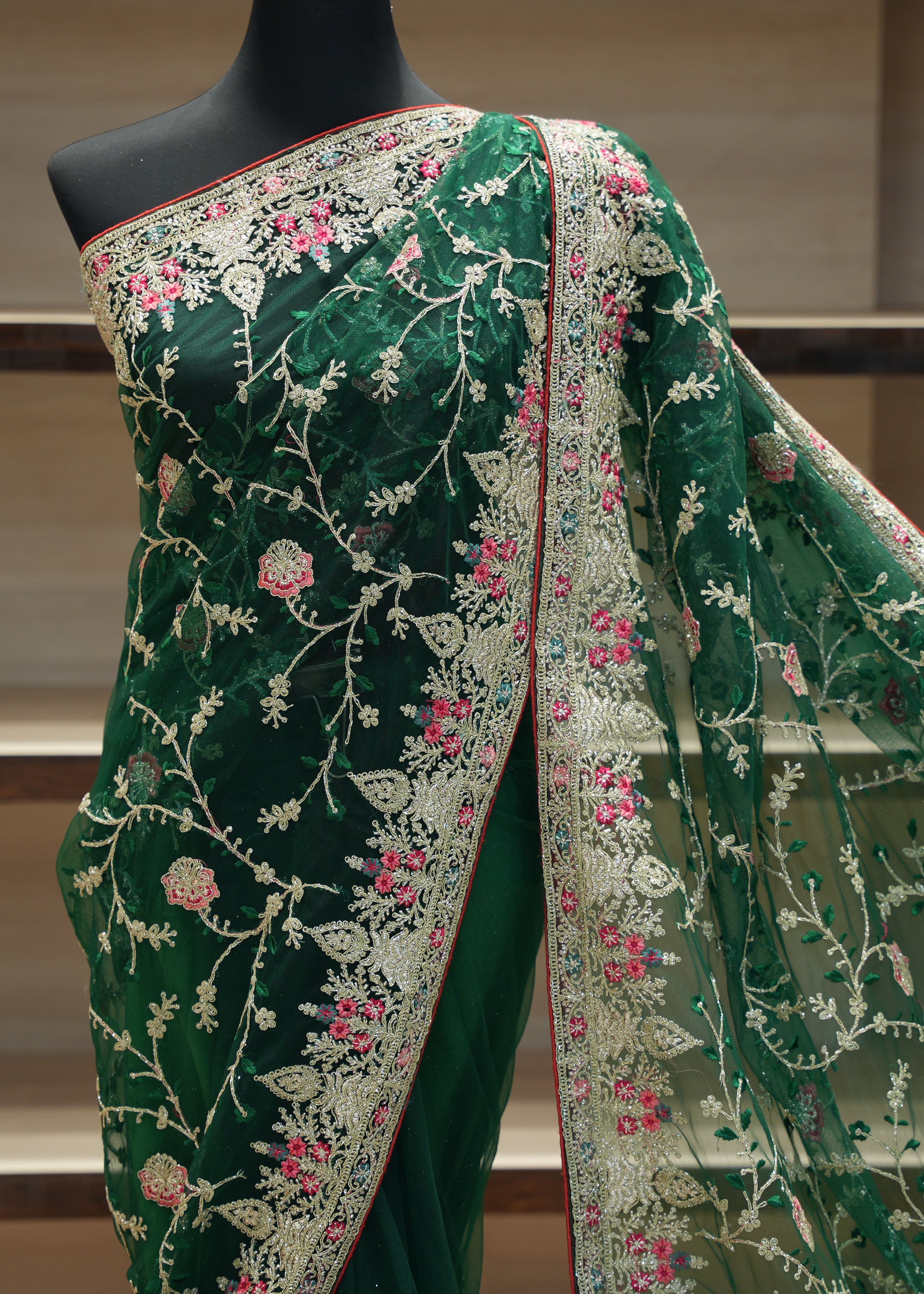 Green embroidered saree with a mannequin on a neutral background