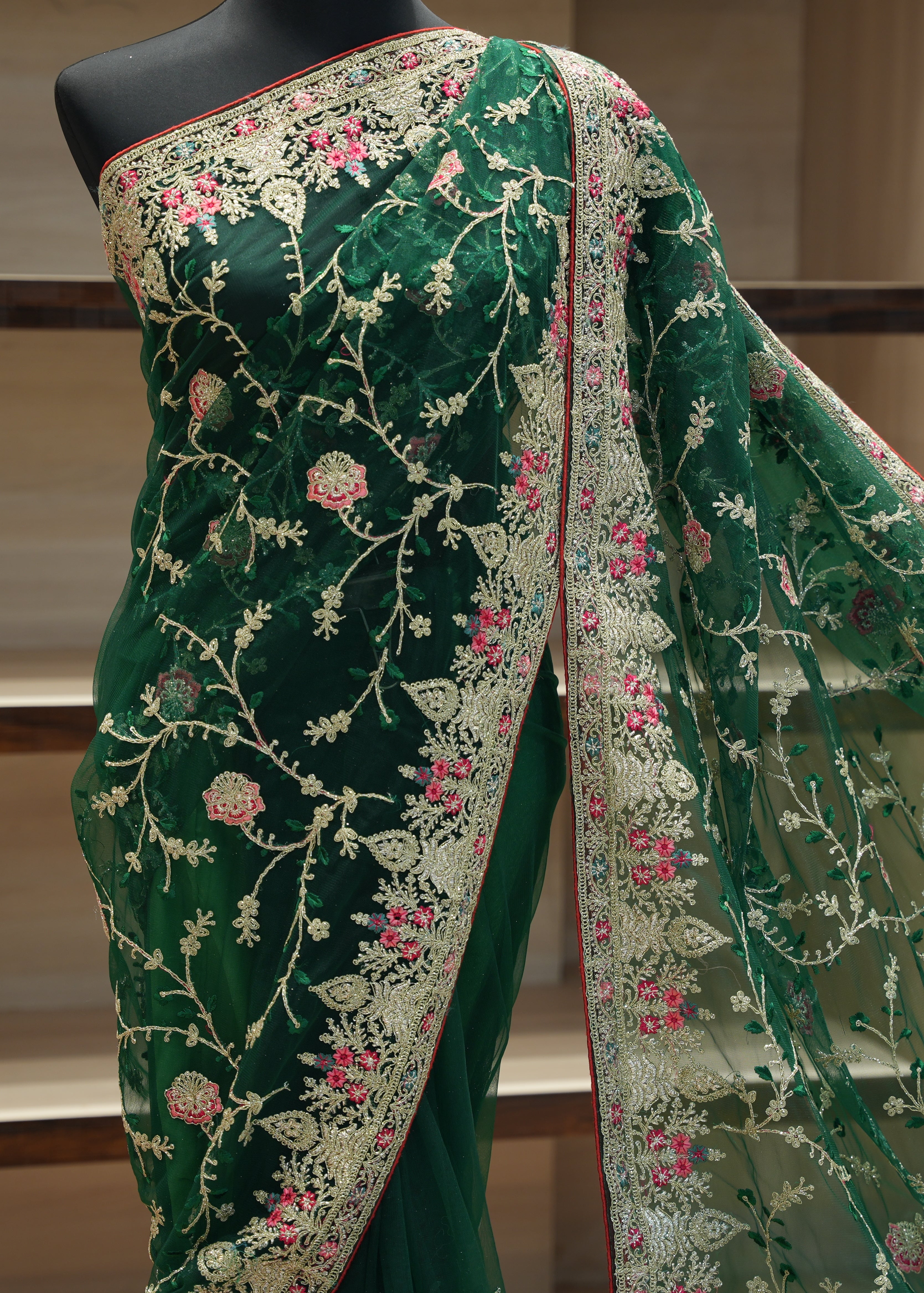 Green embroidered saree with floral patterns on a mannequin against a neutral background