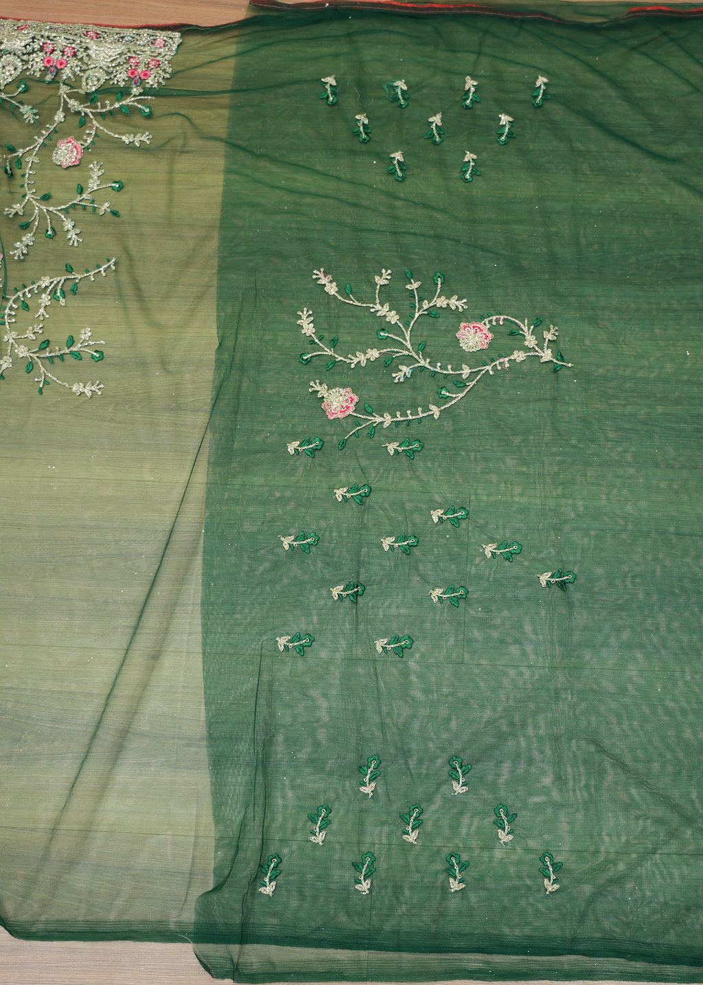 Green fabric with floral embroidery on a wooden surface