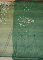 Green fabric with floral embroidery on a wooden surface