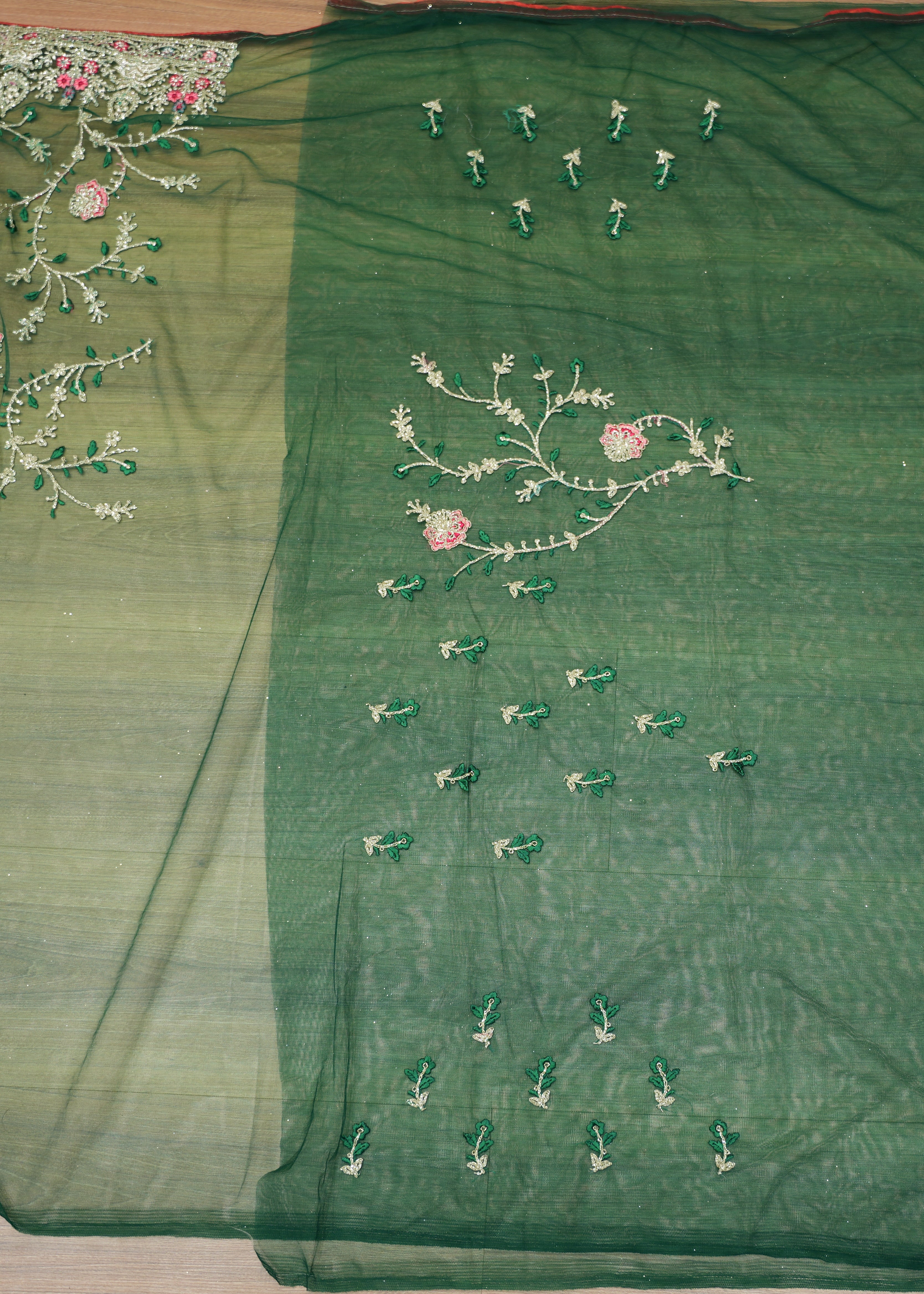 Green fabric with floral embroidery on a wooden surface