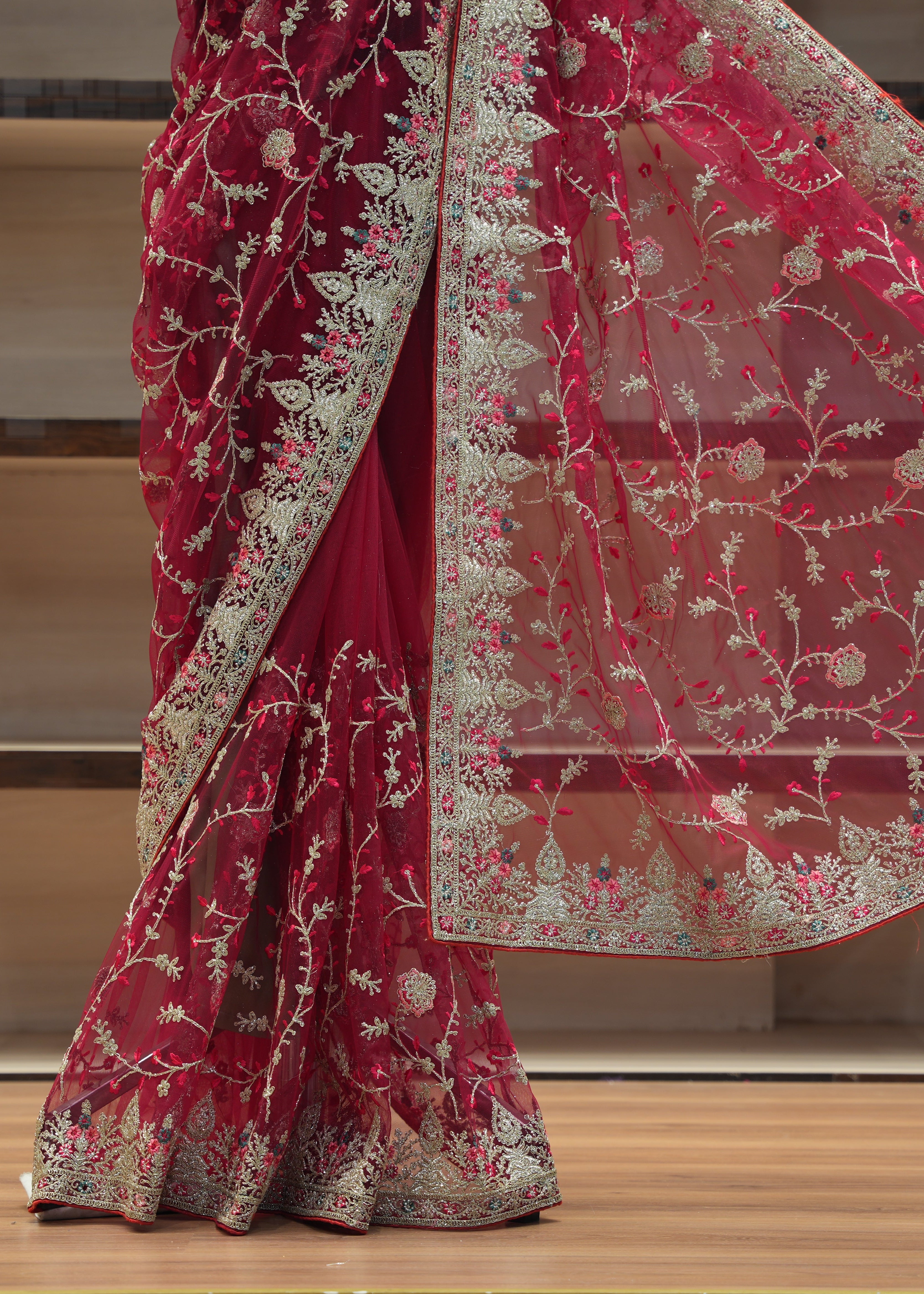 Red saree with white floral embroidery on a wooden floor